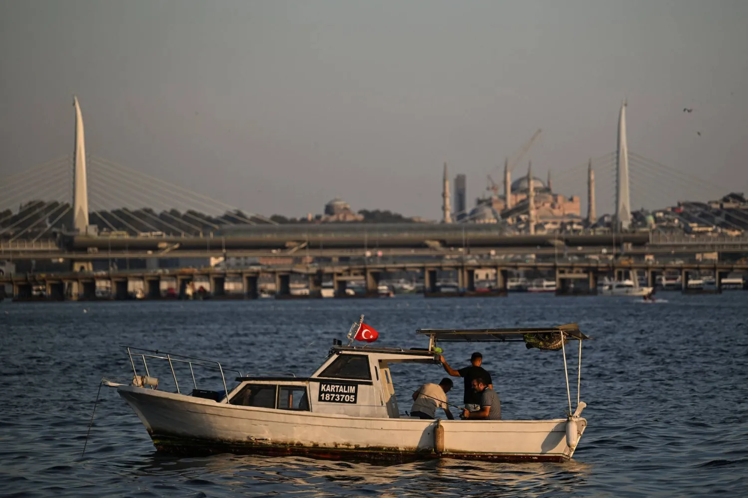 Poople fish on the Golden horn in front of Hagia Sophia Mosque (R) in Istanbul, on September 4, 2025. (Photo by Ozan KOSE / AFP)
