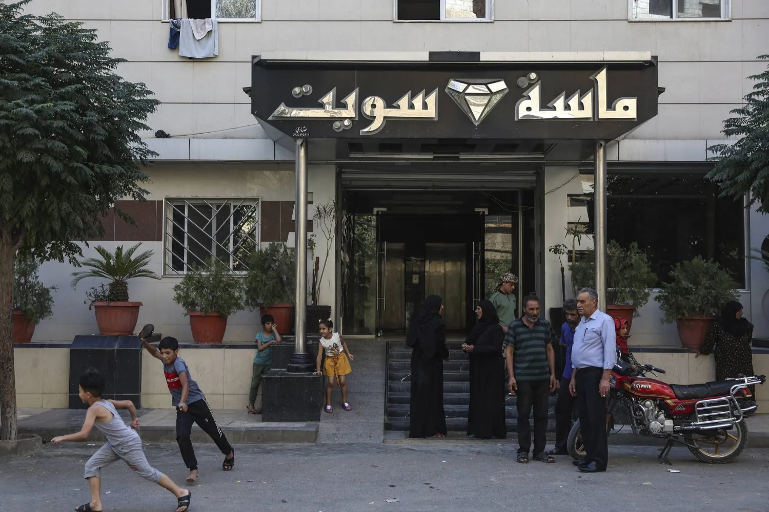 نازحون من بدو السويداء أمام مدخل فندق جرى تحويله إلى مركز إيواء في بلدة السيدة زينب قرب دمشق (أ.ب)