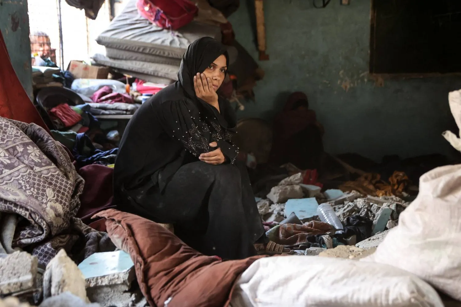 امرأة فلسطينية نازحة تجلس وسط الأنقاض في مدرسة تعرضت لغارة إسرائيلية بمدينة غزة (أ.ف.ب)