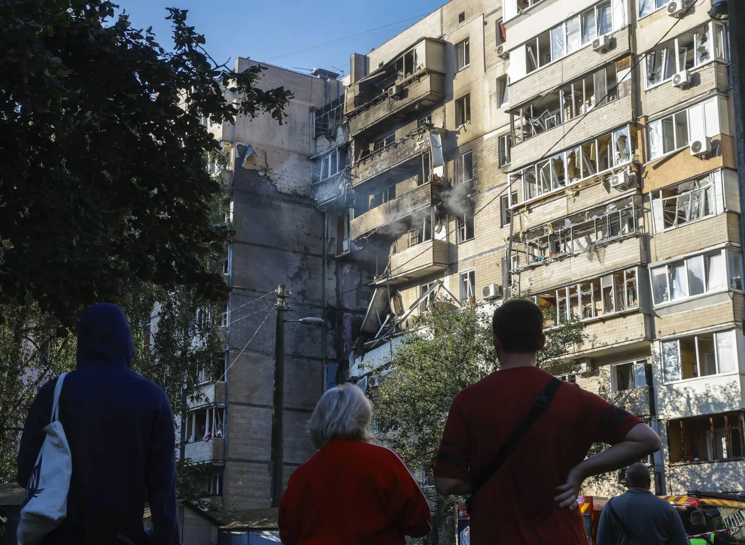 سكان محليون قرب موقع غارة روسية على مبنى سكني من تسعة طوابق في كييف (إ.ب.أ)