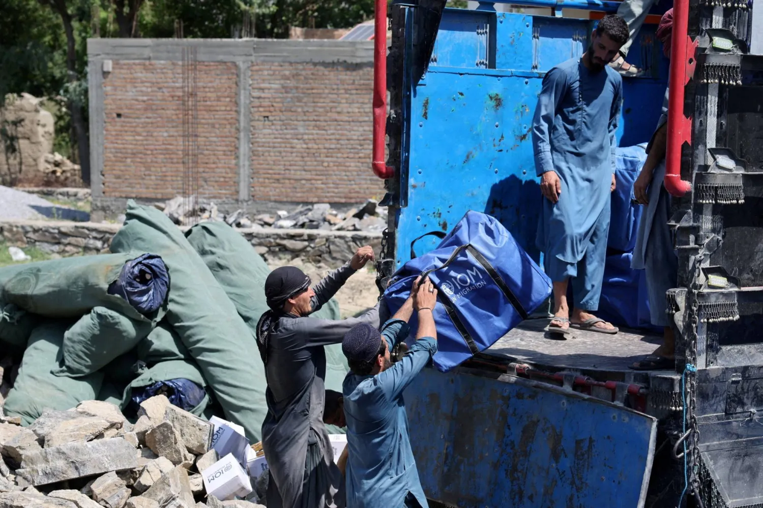 عمال يقومون بتحميل الإمدادات على شاحنة لضحايا الزلزال بمنطقة نورغال بولاية كونار في أفغانستان (رويترز)