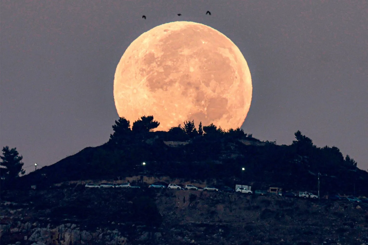 القمر الدموي كما ظهر خلف جبل جرزيم وتم تصويره من نابلس في الضفة الغربية المحتلة (أ.ف.ب)