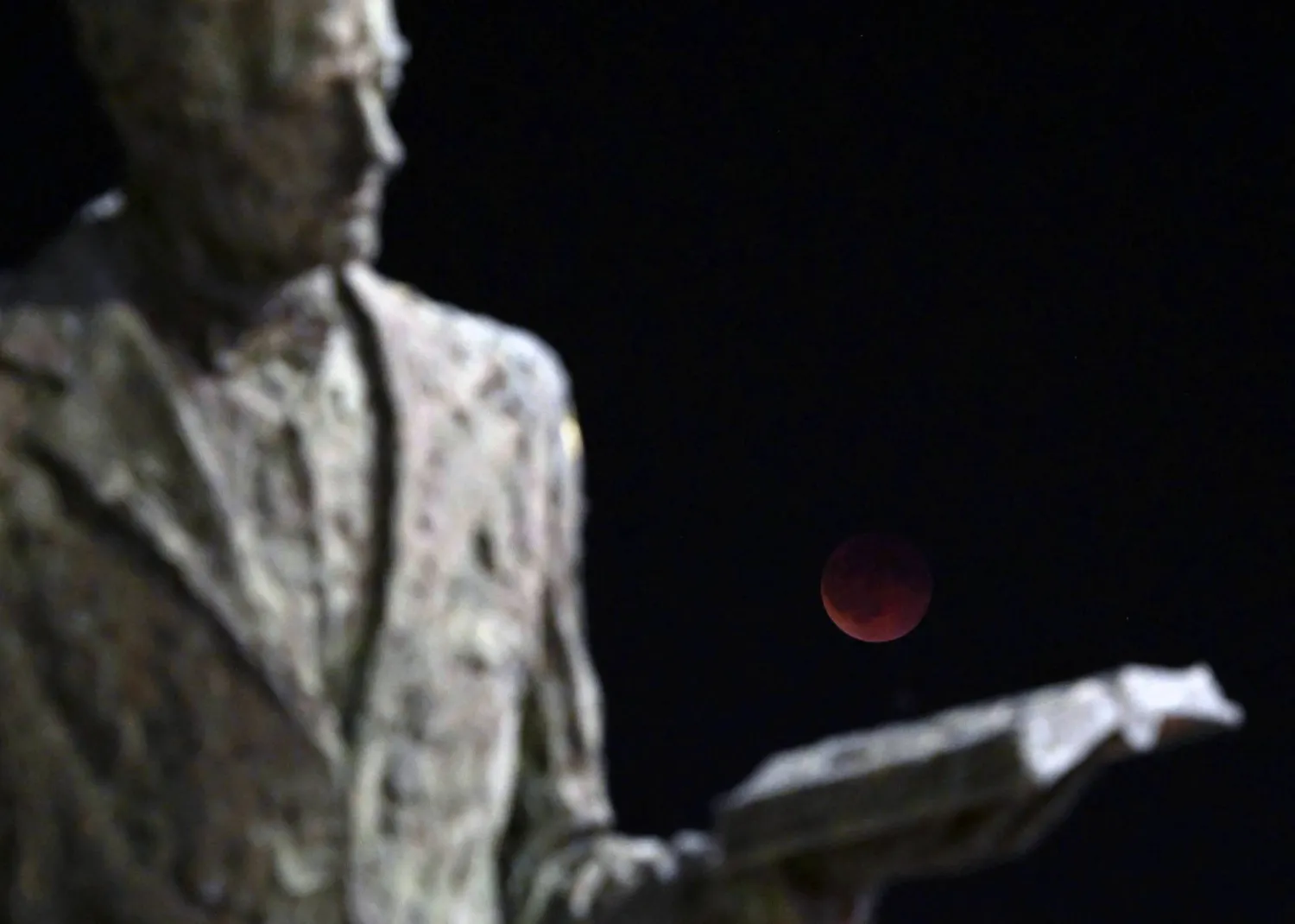 شوهد القمر الدموي خلال خسوف كلي للقمر فوق نصب غيميدجي التذكاري في سكوبيه (أ.ف.ب)