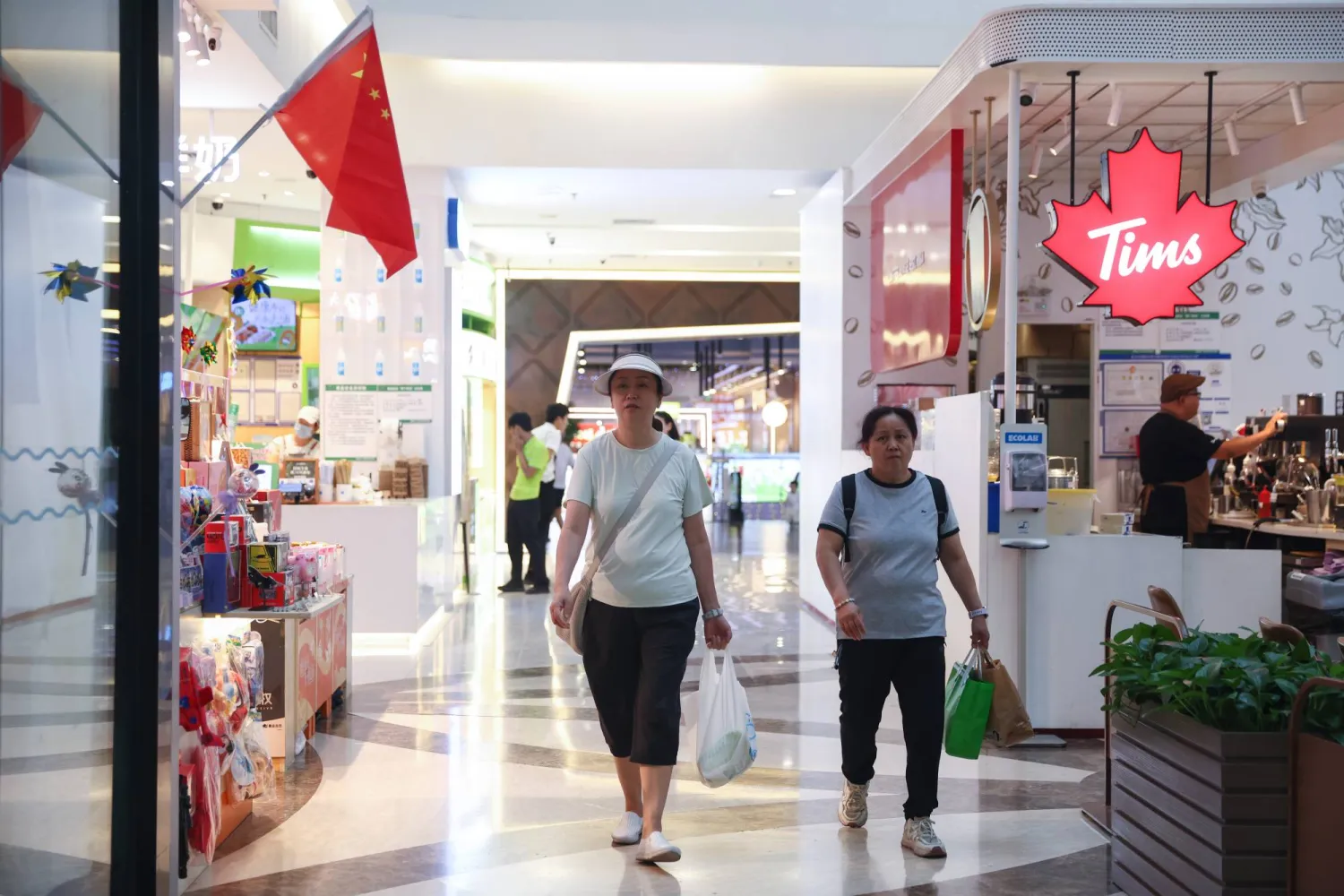 سيدتان في أحد المراكز التجارية بالعاصمة الصينية بكين (إ.ب.أ)