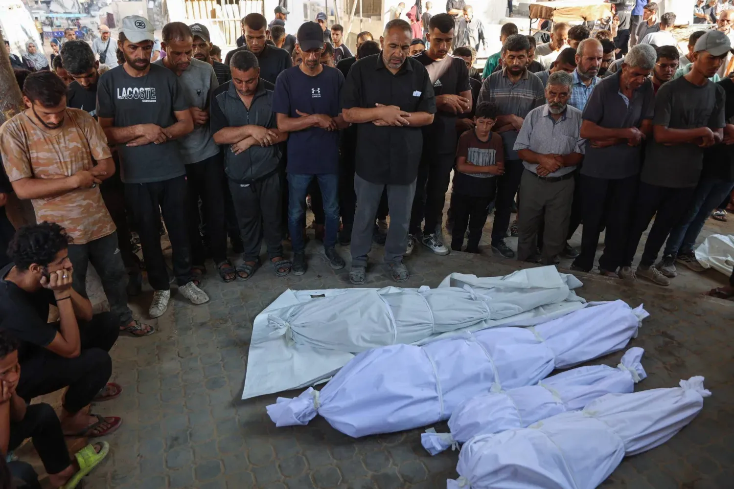 Filistinliler, dün Gazze Şehri'ndeki el-Şifa Hastanesi'nde düzenlenen cenaze töreninde, İsrail hava saldırılarında hayatını kaybedenlerin naaşlarının yanında dua ediyor (AFP)