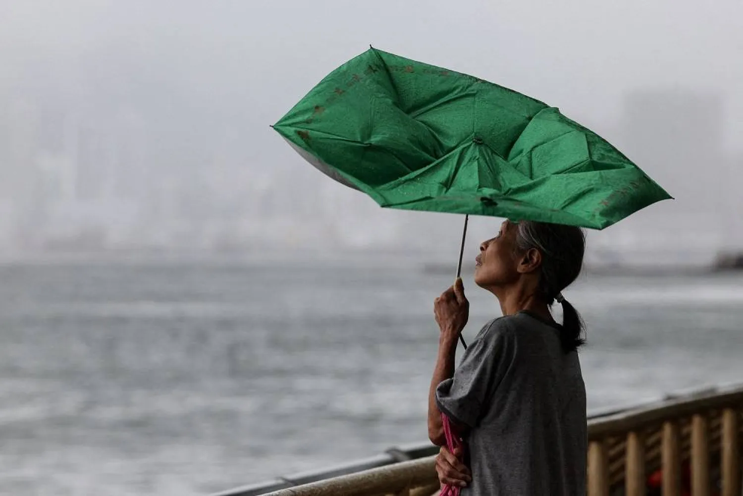 A woman holds an umbrella inverted by winds as Tropical Storm Tapah approaches in Hong Kong, China, September 8, 2025. (Reuters)