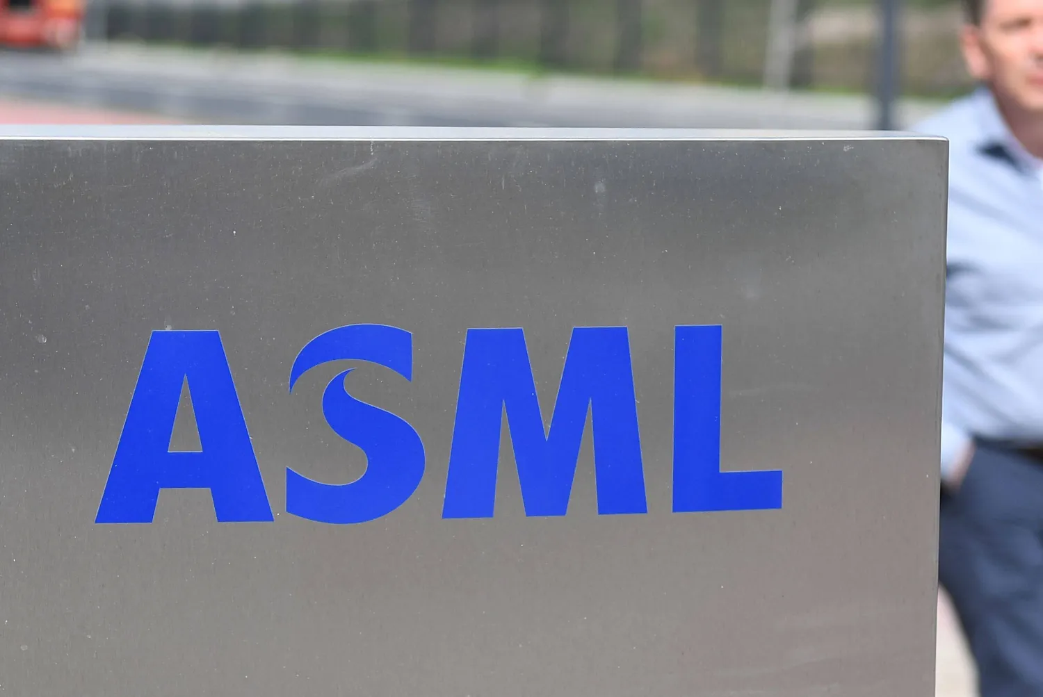 أحد موظفي شركة «إي إس إم إل» الهولندية يمر إلى جانب شعار الشركة في مقرها الرئيسي بمدينة فيلدخوفن (أ.ف.ب) 