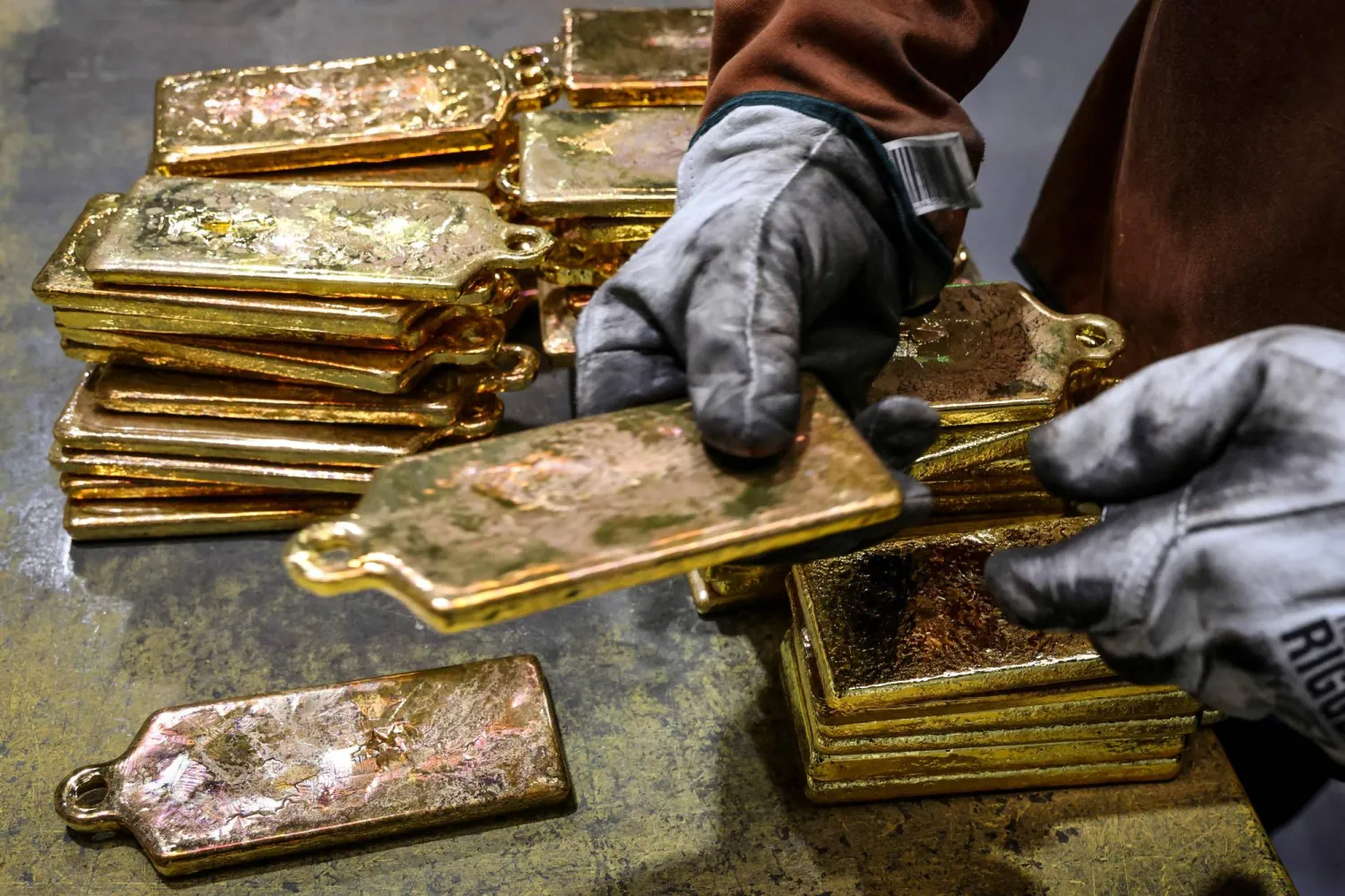 (FILES) A refiner stacks gold bullion after being removed from casts at the ABC Refinery smelter in Sydney on April 29, 2025. (Photo by DAVID GRAY / AFP)