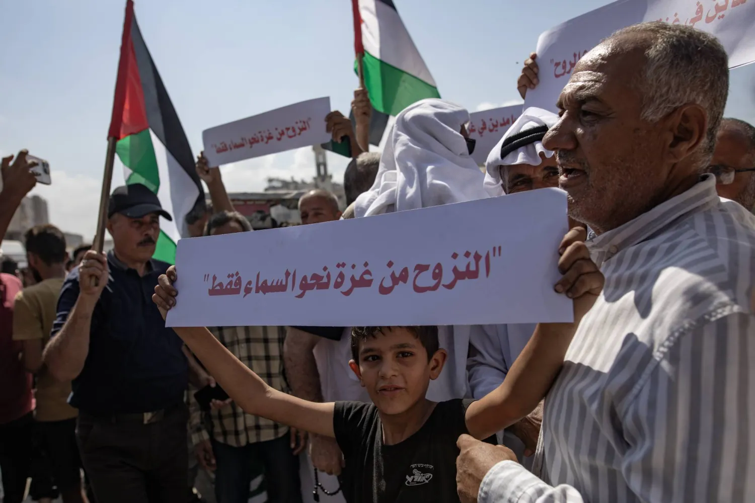 طفل يحمل لافتة تؤكد رفض أهالي مدينة غزة للنزوح خلال مظاهرة يوم الثلاثاء (إ.ب.أ)