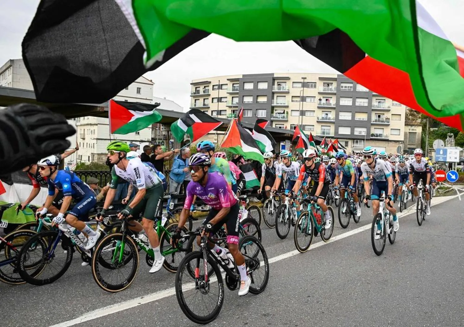 Pro-Palestinian protesters wave flags and shout as the peloton rides by in Poio at the start of the 16th stage of the Vuelta a Espana, a 172 km race between Poio and Castro de Herville, on September 9, 2025. (AFP)