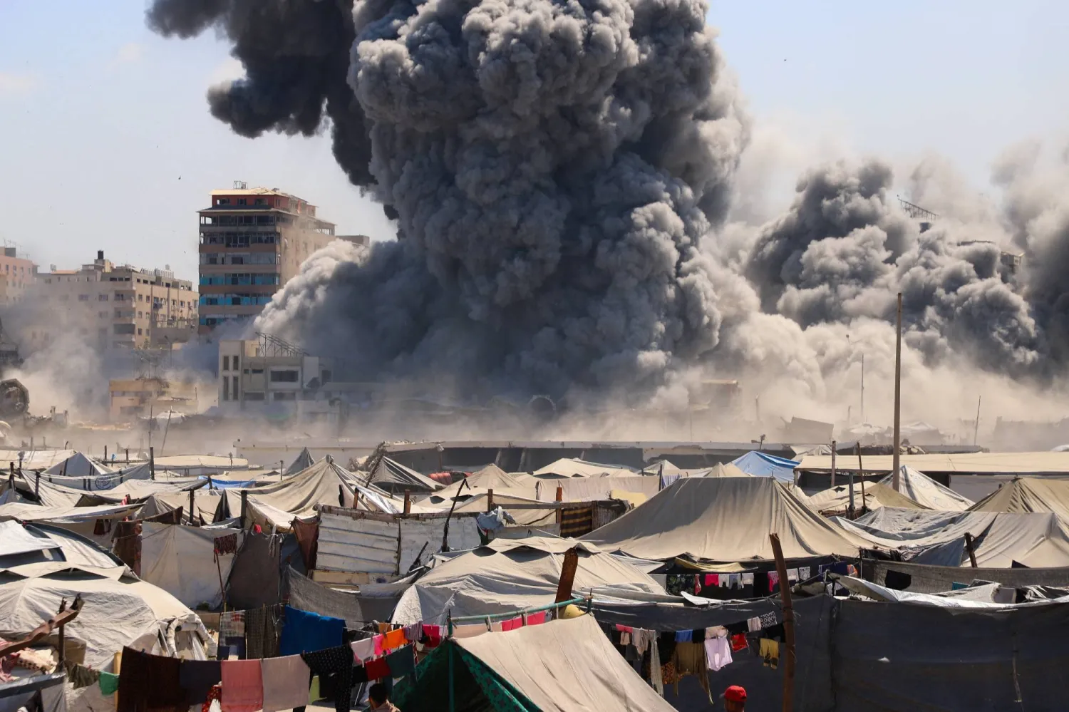 تتصاعد سحب الدخان مع انهيار مبنى سكني كان يؤوي فلسطينيين نازحين بعد أن ضربته غارة جوية إسرائيلية بالقرب من مخيم للنازحين في مدينة غزة (رويترز)