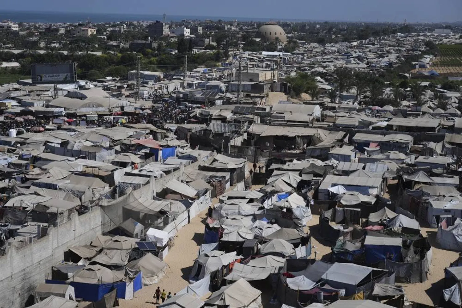 Displaced Palestinians walks through a tent camp in Muwasi, an area that Israel has designated as a safe zone, in Khan Younis southern Gaza Strip, Wednesday, Sept. 10, 2025. (AP) 