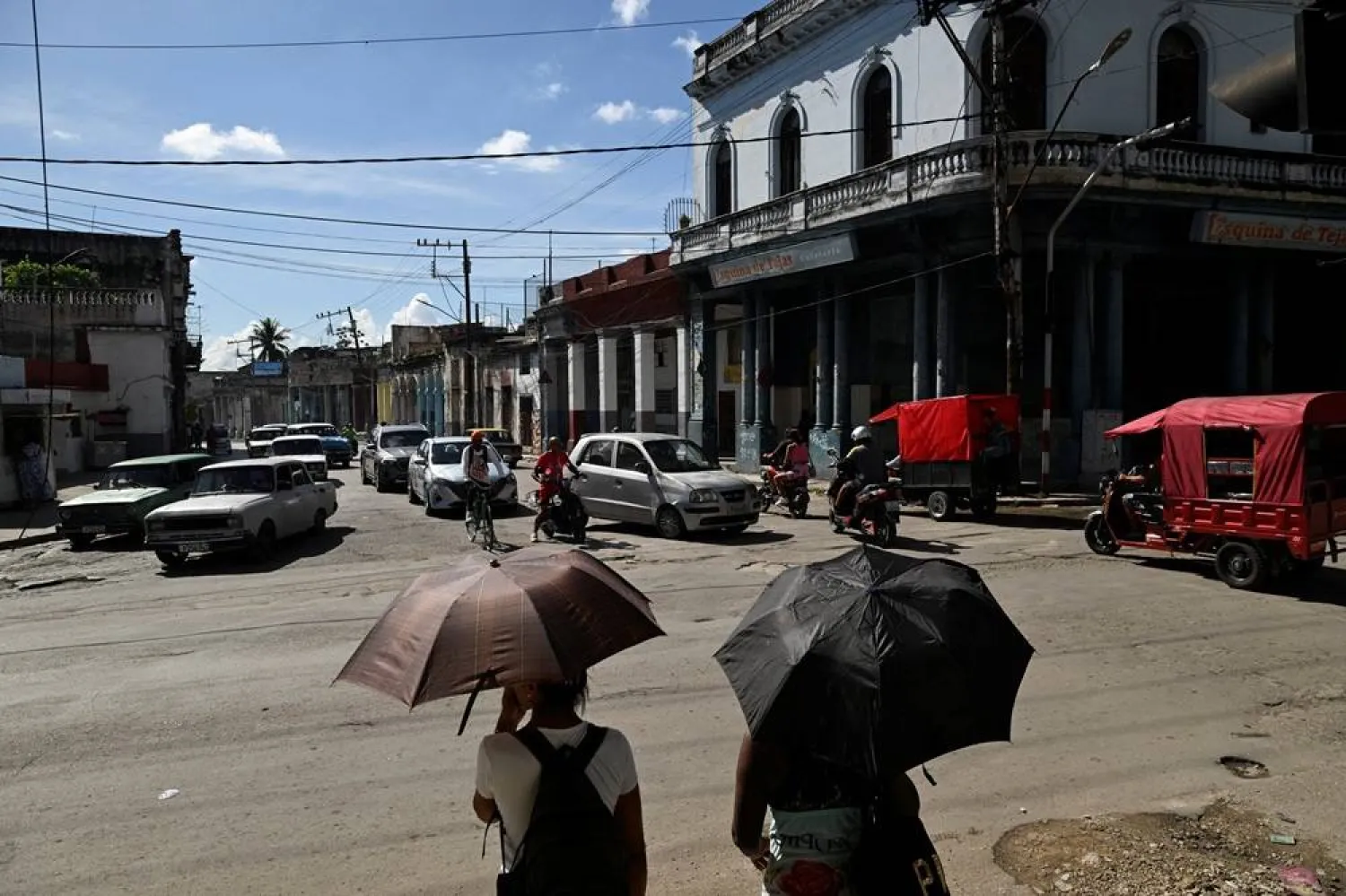 Women hold umbrellas to shield from the sun while waiting to cross a street during a national power grid collapse, for the fourth time in less than a year, which caused a nationwide blackout, in Havana, Cuba, September 10, 2025. (Reuters)