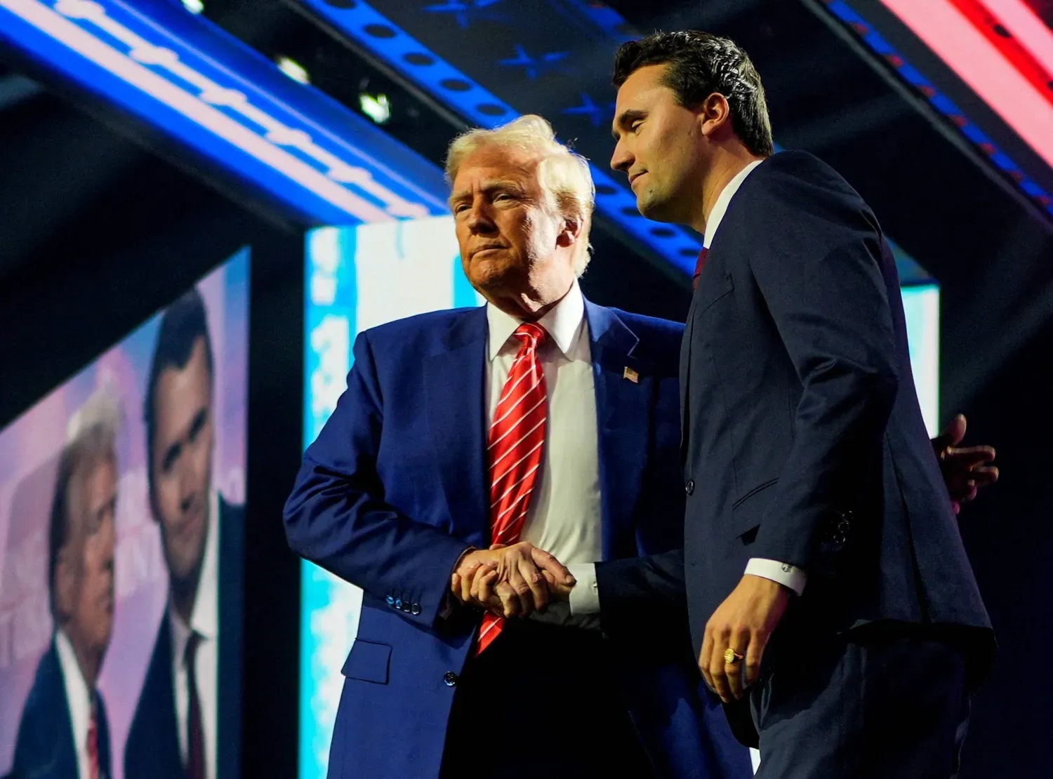 ABD Başkanı Donald Trump, 22 Aralık 2024'te bir seçim kampanyası mitinginde Charlie Kirk ile el sıkışırken (Reuters)