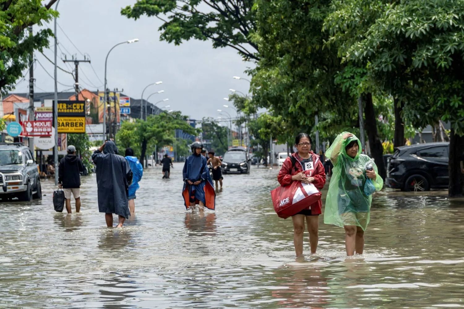 FILE PHOTO: People carrying their belongings wade through a flooded street following overnight heavy rains in Legian, Badung, Bali, Indonesia September 10, 2025. REUTERS/Dicky Bisinglasi/File Photo