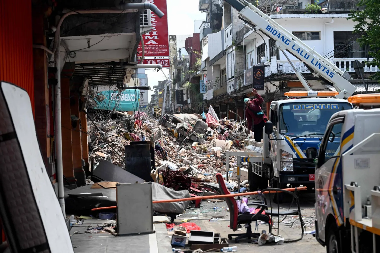 People clean up debris after flooding in Denpasar on Indonesia's resort island of Bali on September 12, 2025. (Photo by SONNY TUMBELAKA / AFP)