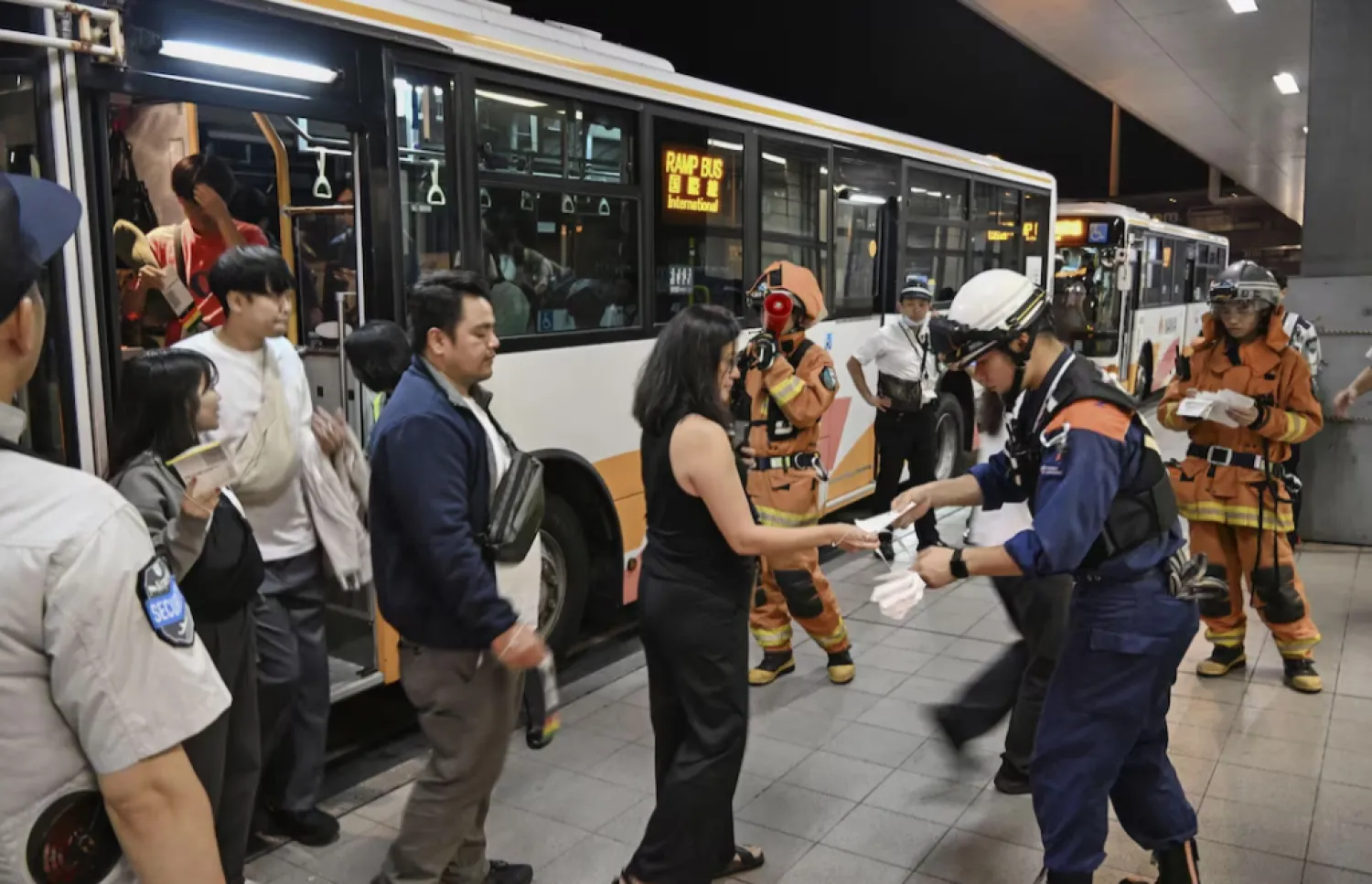 Passengers evacuated via emergency slides from a United Airlines Boeing 737 aircraft, heading to Cebu in the Philippines from Narita Airport near Tokyo, disembark from a bus at the Kansai airport in Izumisano, Osaka prefecture, western Japan September 12, 2025, in this photo taken by Kyodo. Kyodo/via REUTERS