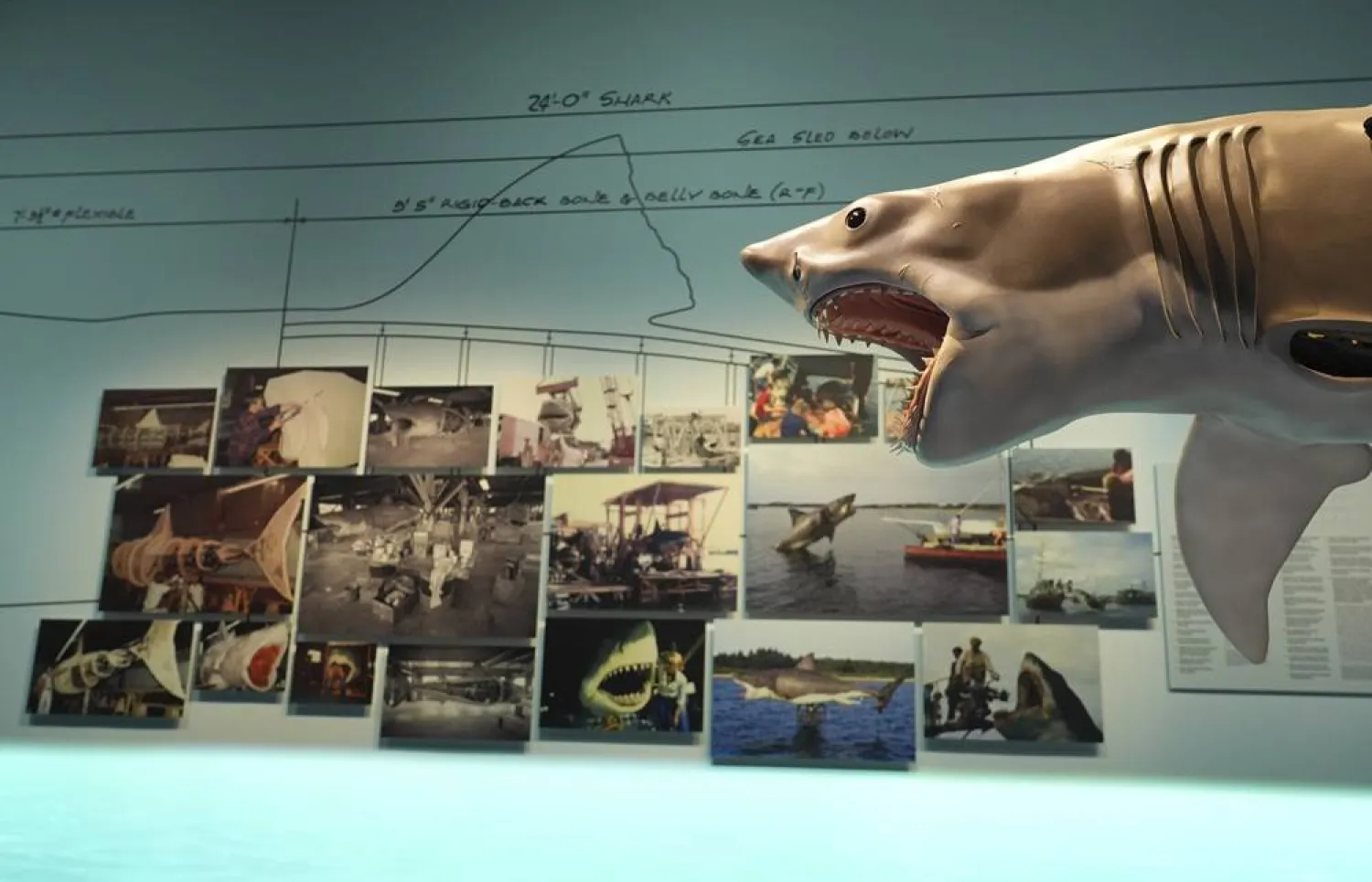  An interactive model based on the shark from the 1975 film "Jaws" looms over photographs from the production during the "Jaws: The Exhibition" press preview on Wednesday, Sept. 10, 2025, at the Academy Museum of Motion Pictures in Los Angeles. (AP) 