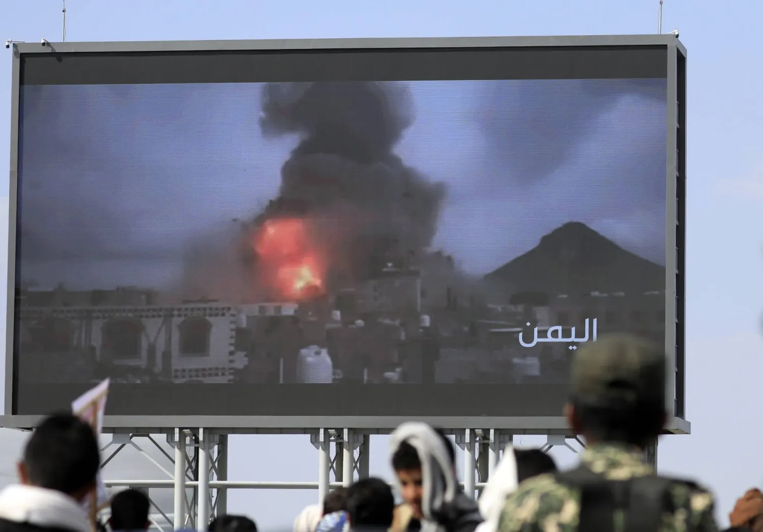 تجمع أنصار الحوثيين أمام لوحة إعلانية رقمية تُظهر انفجارات ناجمة عن الغارات الإسرائيلية الأخيرة على موقع في صنعاء خلال احتجاج ضد إسرائيل في العاصمة (إ.ب.أ)