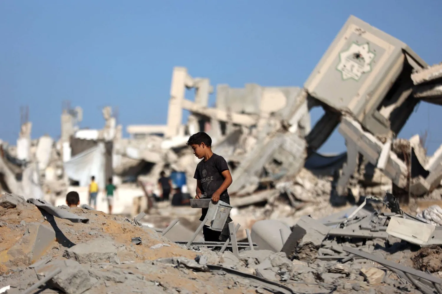 A displaced Palestinian boy stands amid the rubble of a building, levelled in an overnight Israeli strike that also damaged the surrounding tents used as temporary shelters, in the Rimal neighborhood of Gaza City on September 13, 2025. (Photo by Omar AL-QATTAA / AFP)