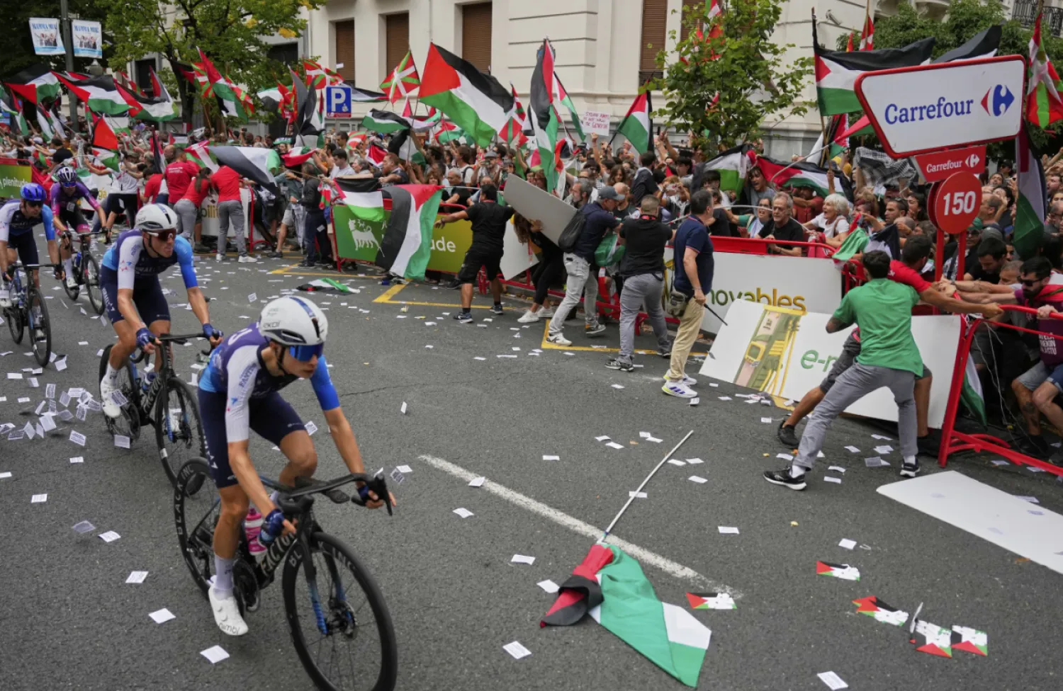 Riders of the Israel Premier Tech team compete as people holding Palestinian flags try to disrupt the eleventh stage of the Spanish Vuelta cycling race, from Bilbao to Bilbao, Spain, Wednesday, Sept. 3, 2025. (AP Photo/Miguel Oses)