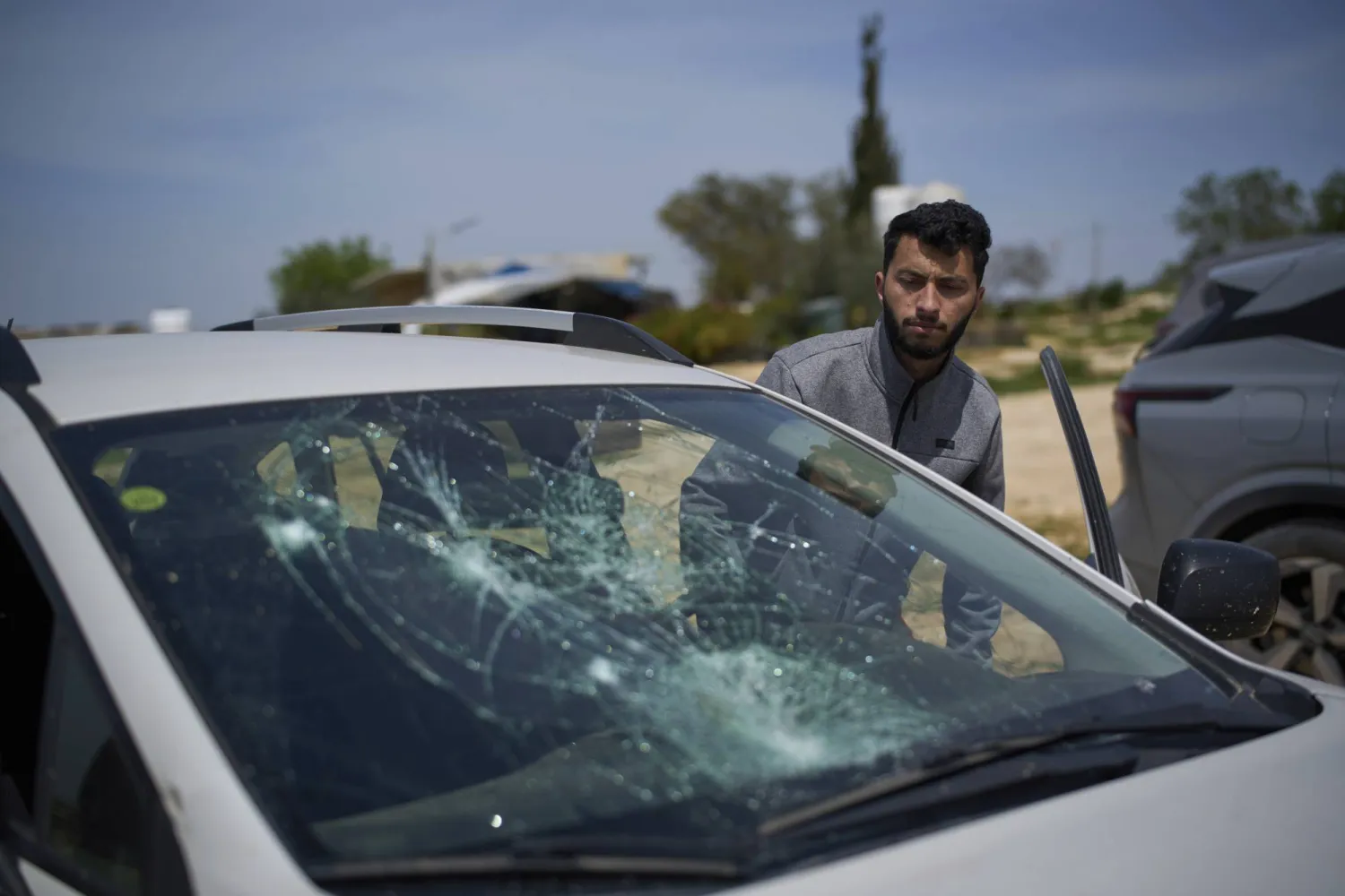 باسل عدرا المخرج الفلسطيني المشارك في الفيلم الوثائقي الحائز جائزة الأوسكار «لا أرض أخرى» ينظر إلى سيارة متضررة بعد هجوم مستوطن في قرية سوسيا في الضفة الغربية - 25 مارس 2025 (أ.ب)