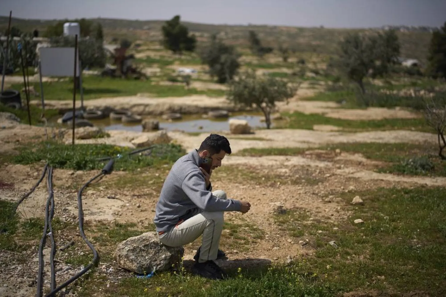 Basel Adra, one of the directors of the Oscar winner documentary "No Other Land", speaks on the phone as he sits in an area near the house of Palestinian co-director Hamdan Ballal, in Susiya in Masafer Yatta, south Hebron hills, March 25, 2025. (AP) 