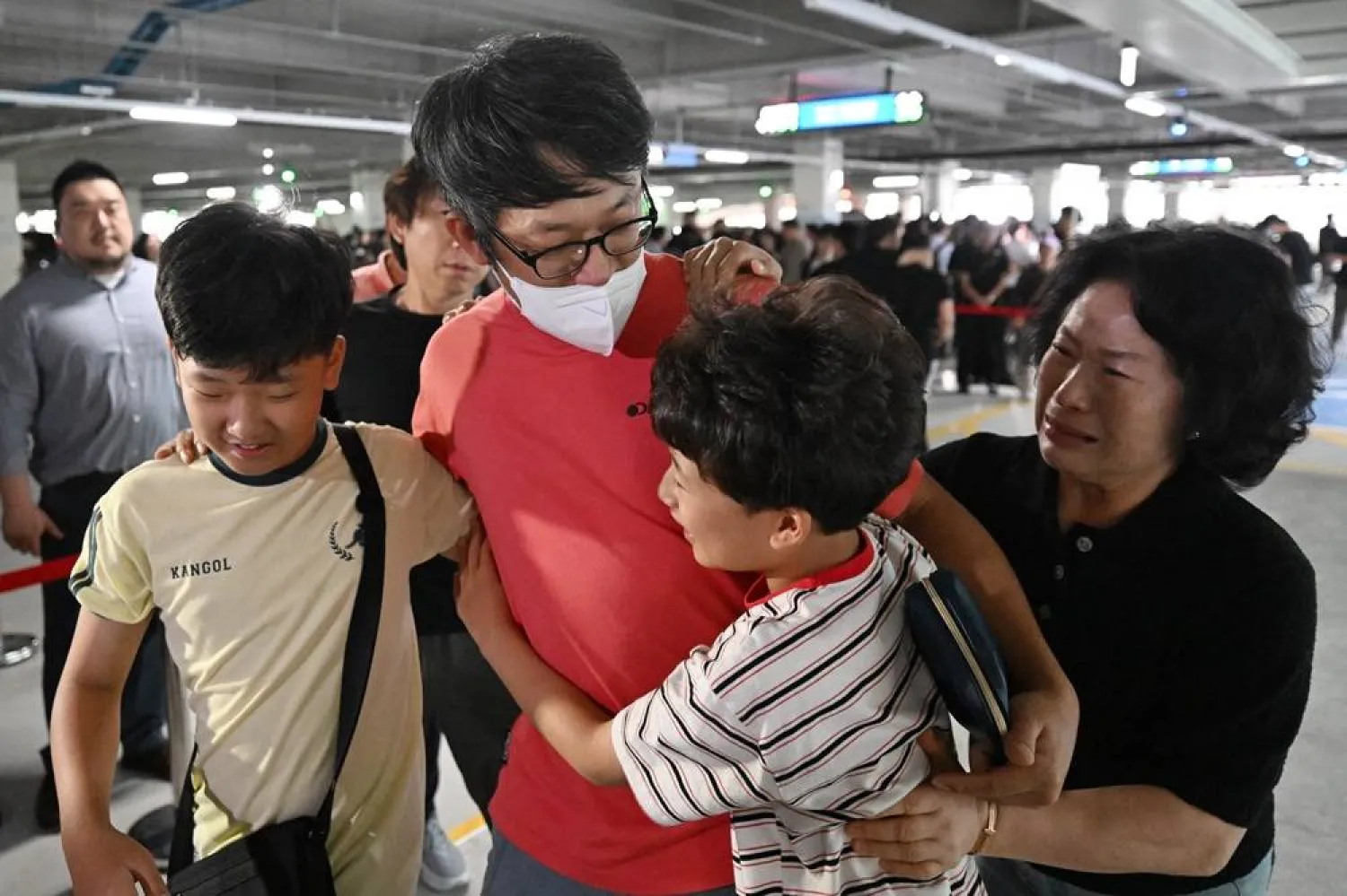 A South Korean worker (2nd L), who was detained in a US immigration raid at a Hyundai-LG plant in Ellabell, Georgia, is welcomed by family members after returning from Atlanta at a parking lot in Incheon International Airport in Incheon on September 12, 2025. (Yonhap/ AFP)