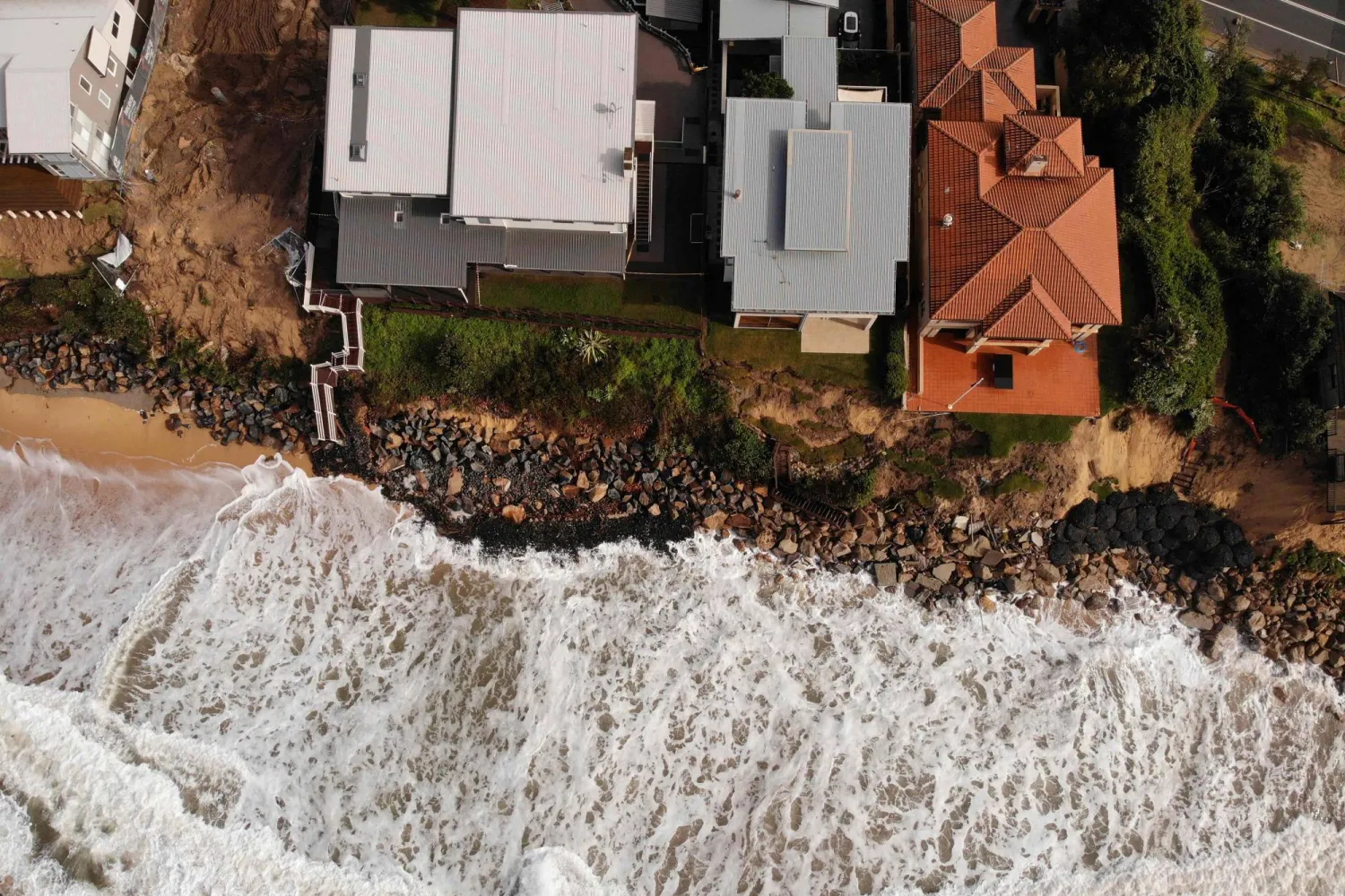 (FILES) An aerial file photo taken on July 28, 2020 shows homes perched on Australia's eastern coastal town of Wamberal that are at risk of being swept away, after days of driving rain, high winds and monster swells smashed the coastline. (Photo by Peter PARKS / AFP)