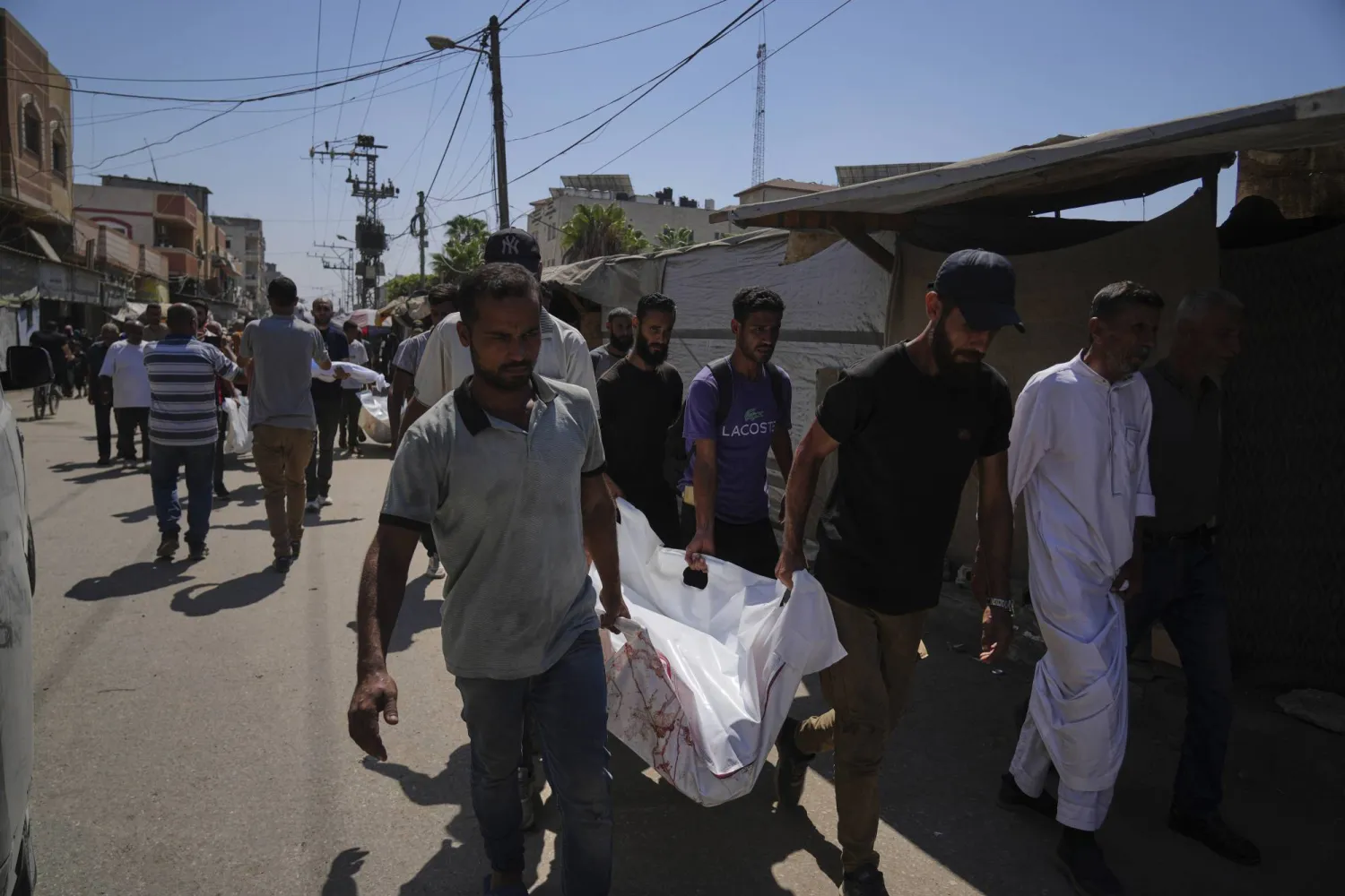 فلسطينيون يحملون جثمان سيدة فلسطينية تُدعى علياء أبو عودة قُتلت أمس في غارات إسرائيلية على دير البلح (أ.ب)