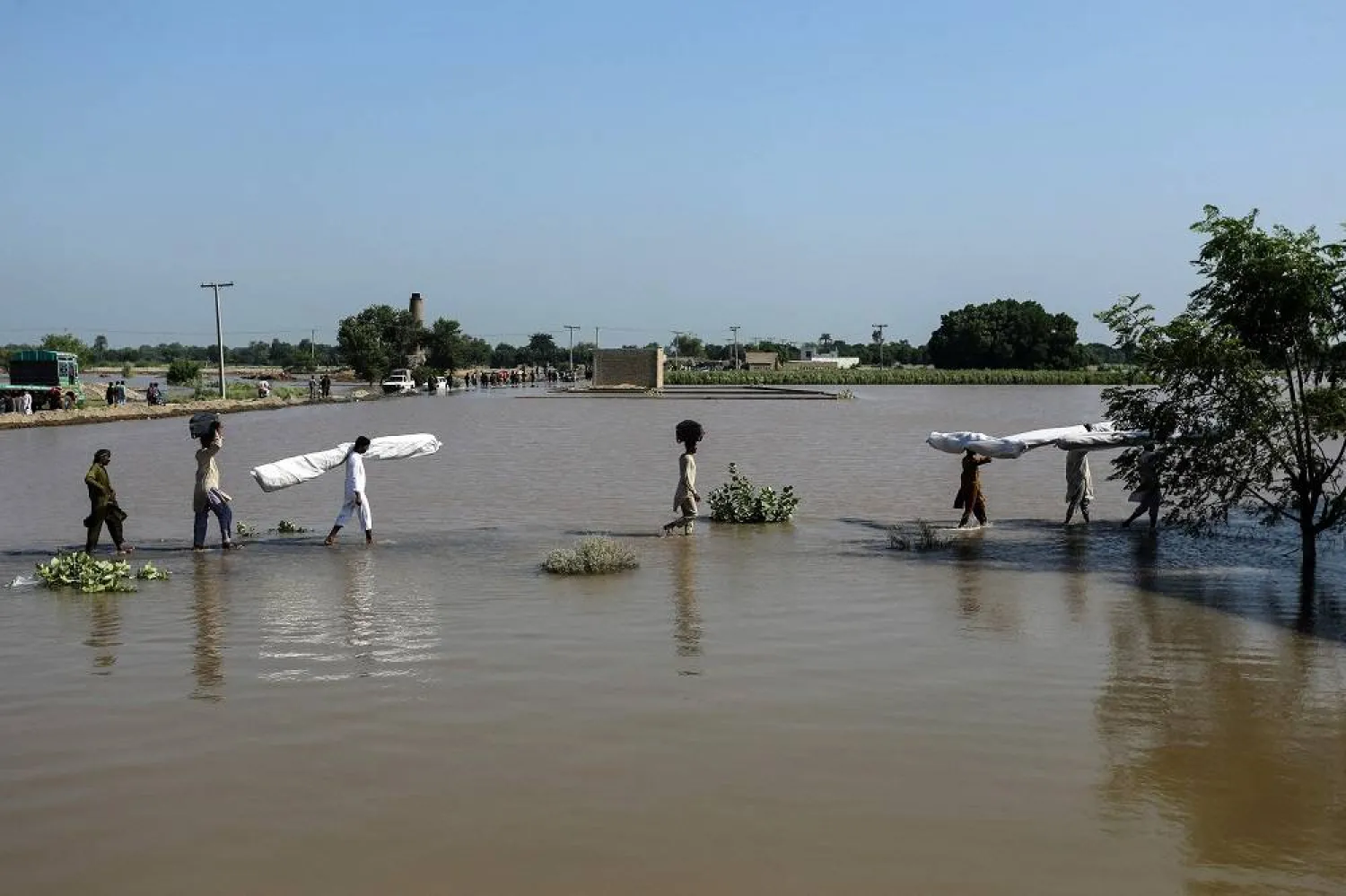 Flood-affected people carry makeshift tents as they wade through floodwaters at Alipur in the Muzaffargarh district of Punjab province on September 13, 2025. (AFP) 