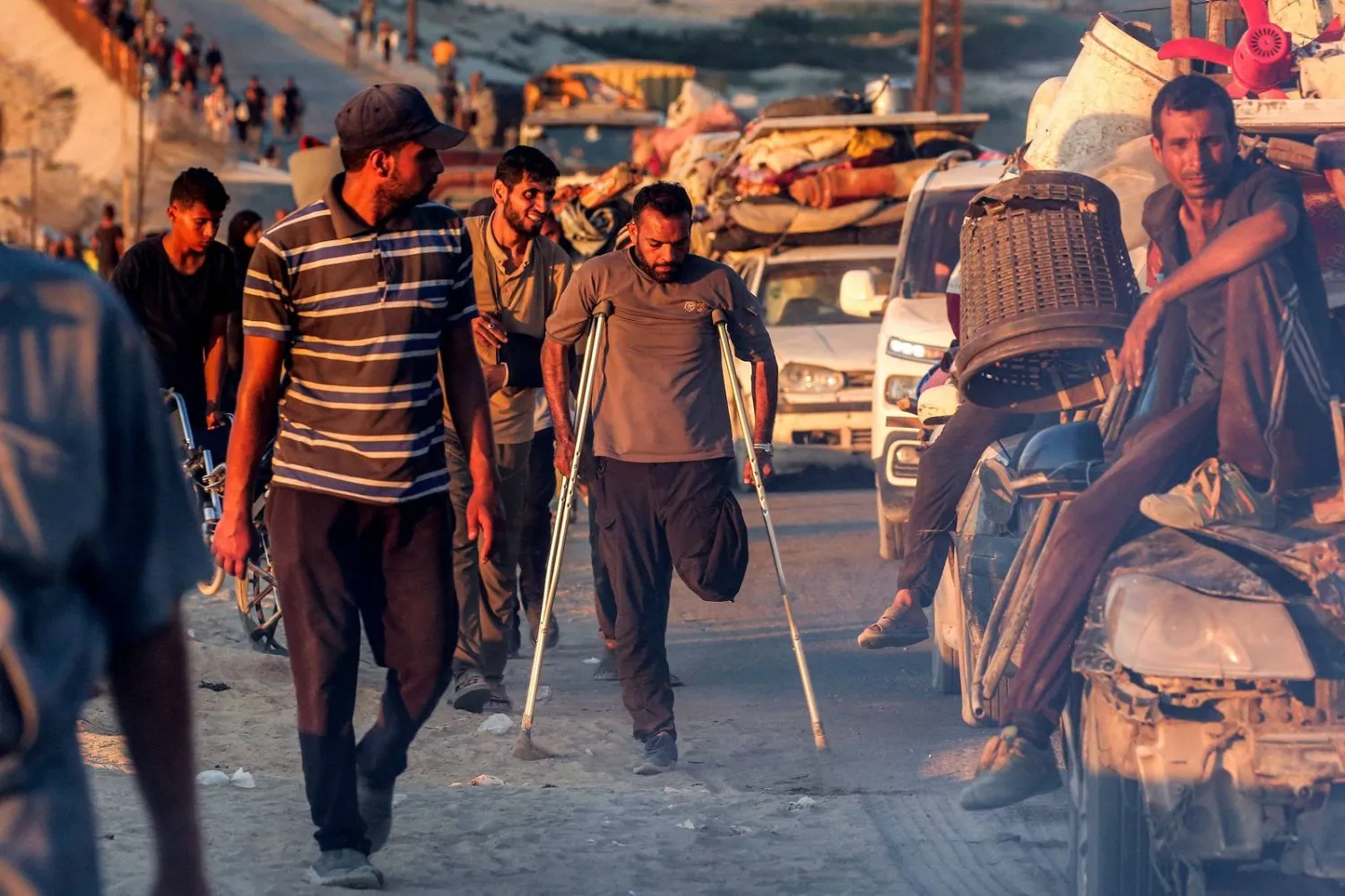 فلسطيني مبتور الساق يسير متكئاً على عكازين إلى جانب نازحين آخرين متجهين جنوباً من مدينة غزة (أ.ف.ب)