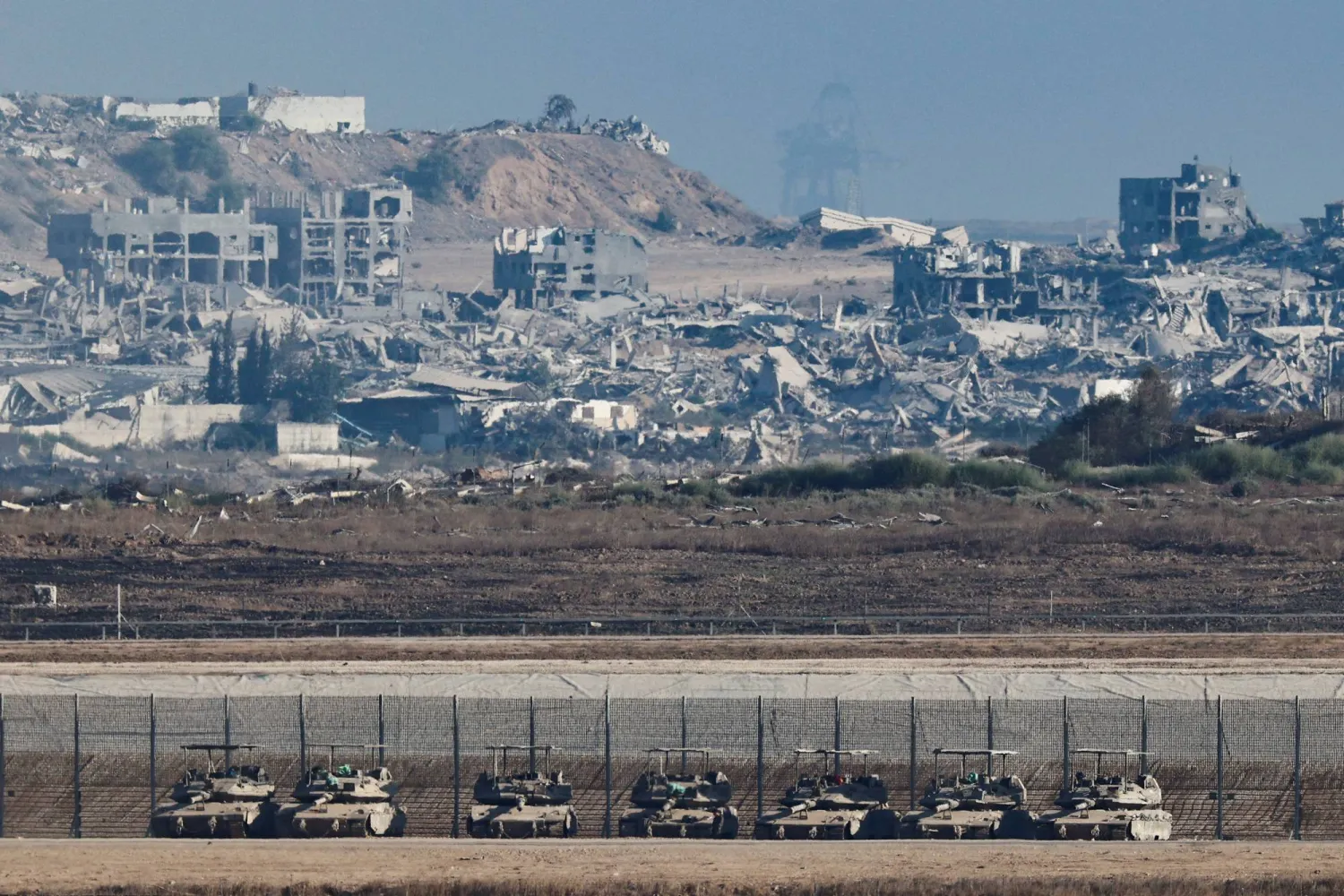 Gazze sınırının İsrail tarafında tanklar, arka planda ise Şeridin büyük çaplı yıkımı görülüyor (Reuters)