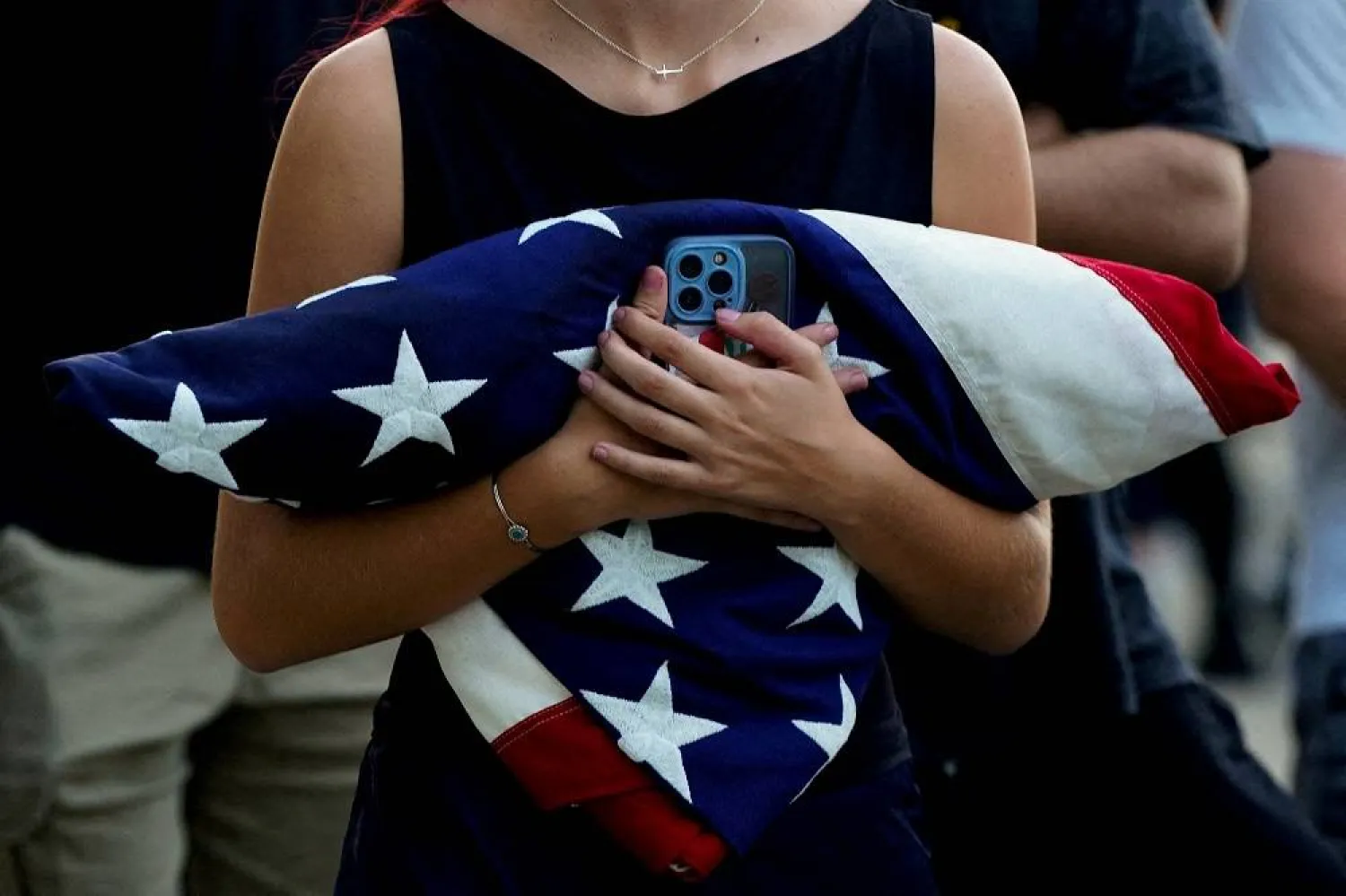 A woman holds a folded US flag while waiting in line with other people to attend a vigil for conservative activist Charlie Kirk, who was fatally shot during an event at Utah Valley University, at the Kennedy Center in Washington, DC, US, September 14, 2025. (Reuters)  