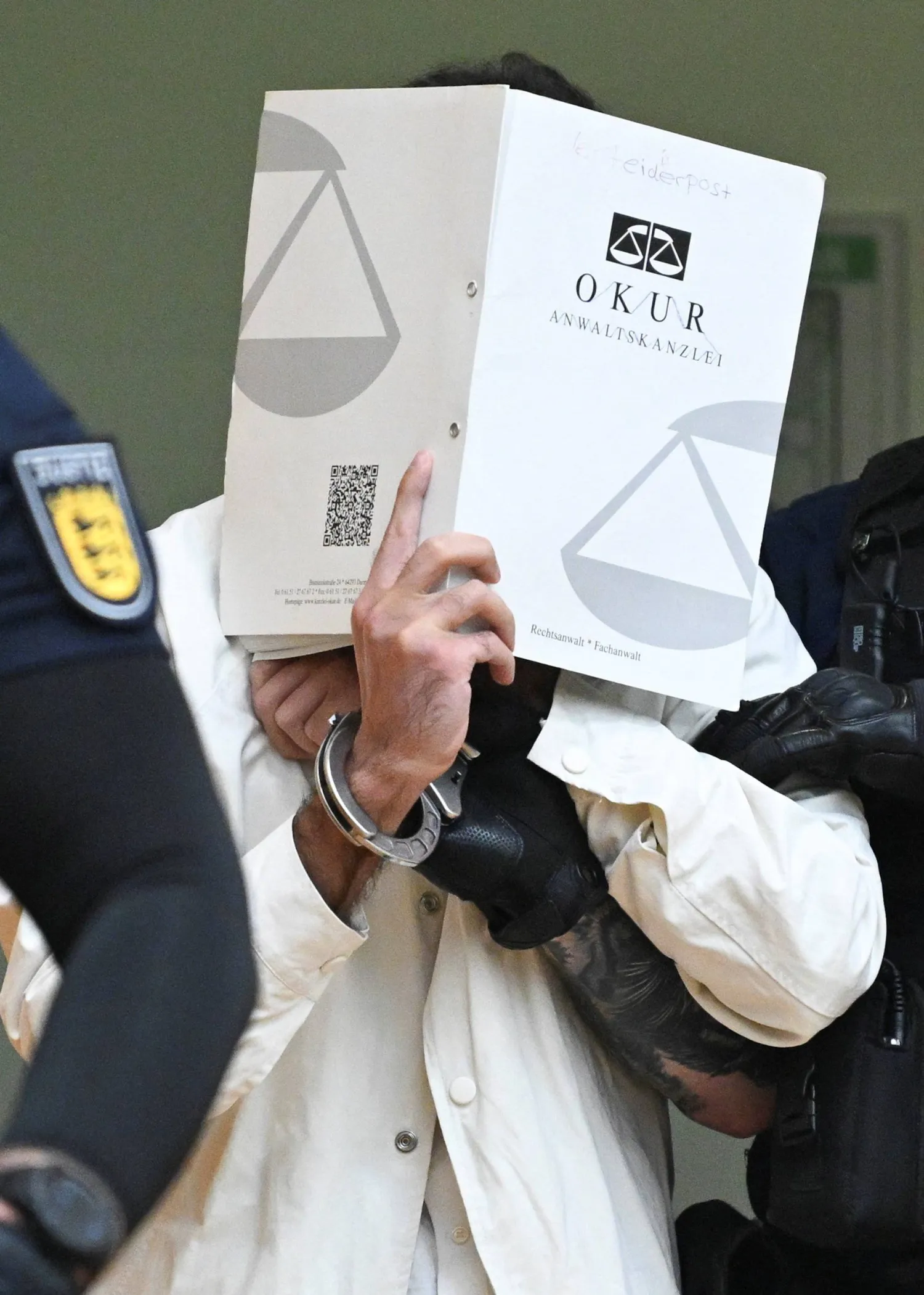 يصل المتهم سليمان وهو يغطي وجهه بملف إلى قاعة المحكمة الإقليمية العليا في شتوتغارت في 16 سبتمبر 2025 لحضور محاكمة بتهمة قتل ضابط شرطة وإصابة 5 آخرين أواخر مايو 2024 (رويترز)