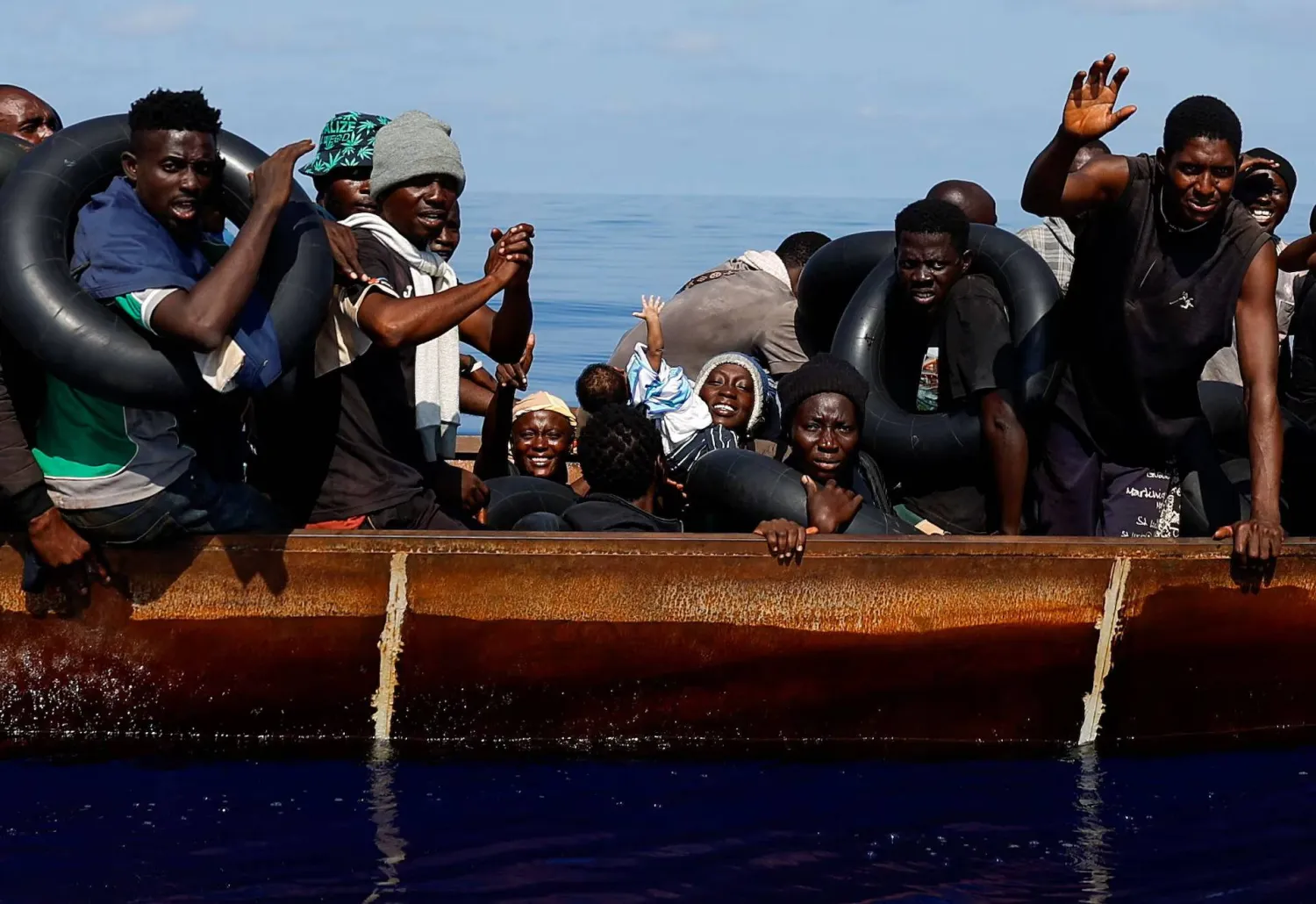 امرأة تحمل طفلها في أثناء إبحارهما على متن قارب حديدي في المياه الدولية جنوب لامبيدوزا وسط البحر المتوسط (رويترز - أرشيفية)