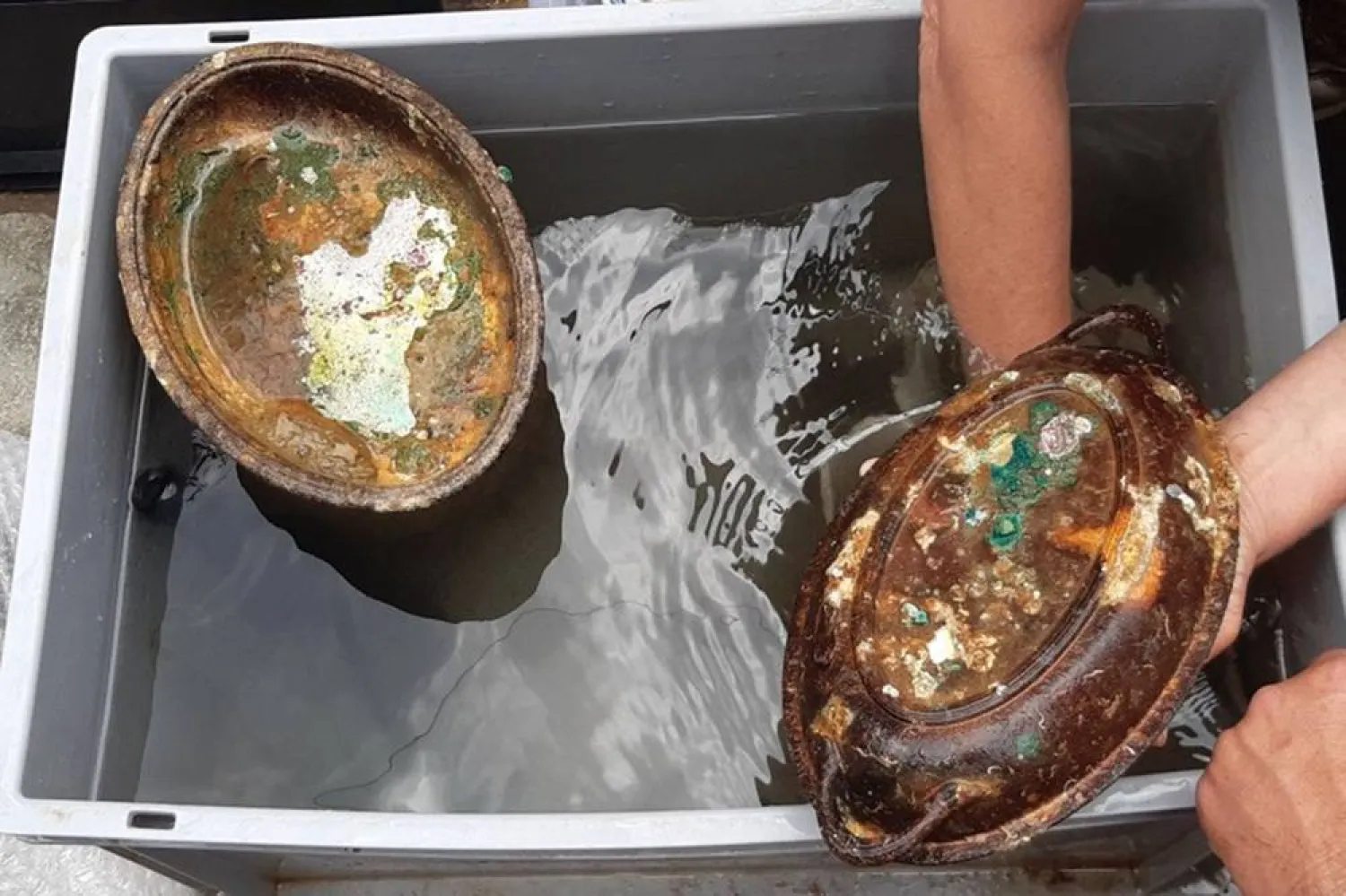 A handout photo obtained from the Greek Ministry of Culture on September 15, 2025 shows a member of a Greek-British search team holding a silver serving tray from the HMHS Britannic, a British hospital ship that sank near the Greek island of Kea in 1916 after hitting a mine during World War I. (Greek Culture Ministry / AFP) 
