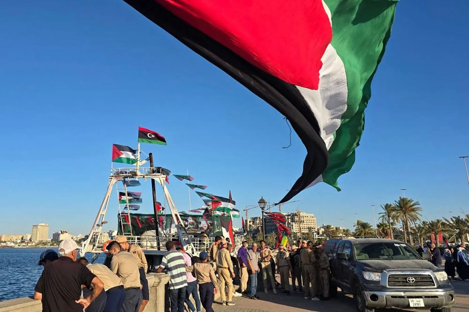 People pose for a picture in front of the Omar al-Mukhtar ship, a Libyan ship setting sail on September 17 to join the Global Sumud Flotilla, at the port in Tripoli on September 16, 2025. (AFP)