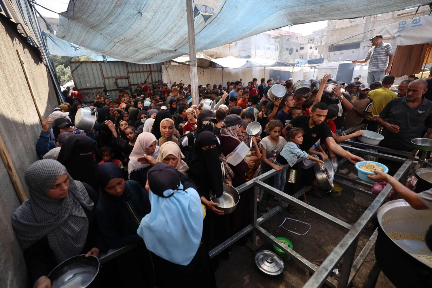 فلسطينيون يحملون أوانيهم أمام مطبخ خيري في مخيم النصيرات للاجئين وسط قطاع غزة 14 سبتمبر 2025 (أ.ف.ب)