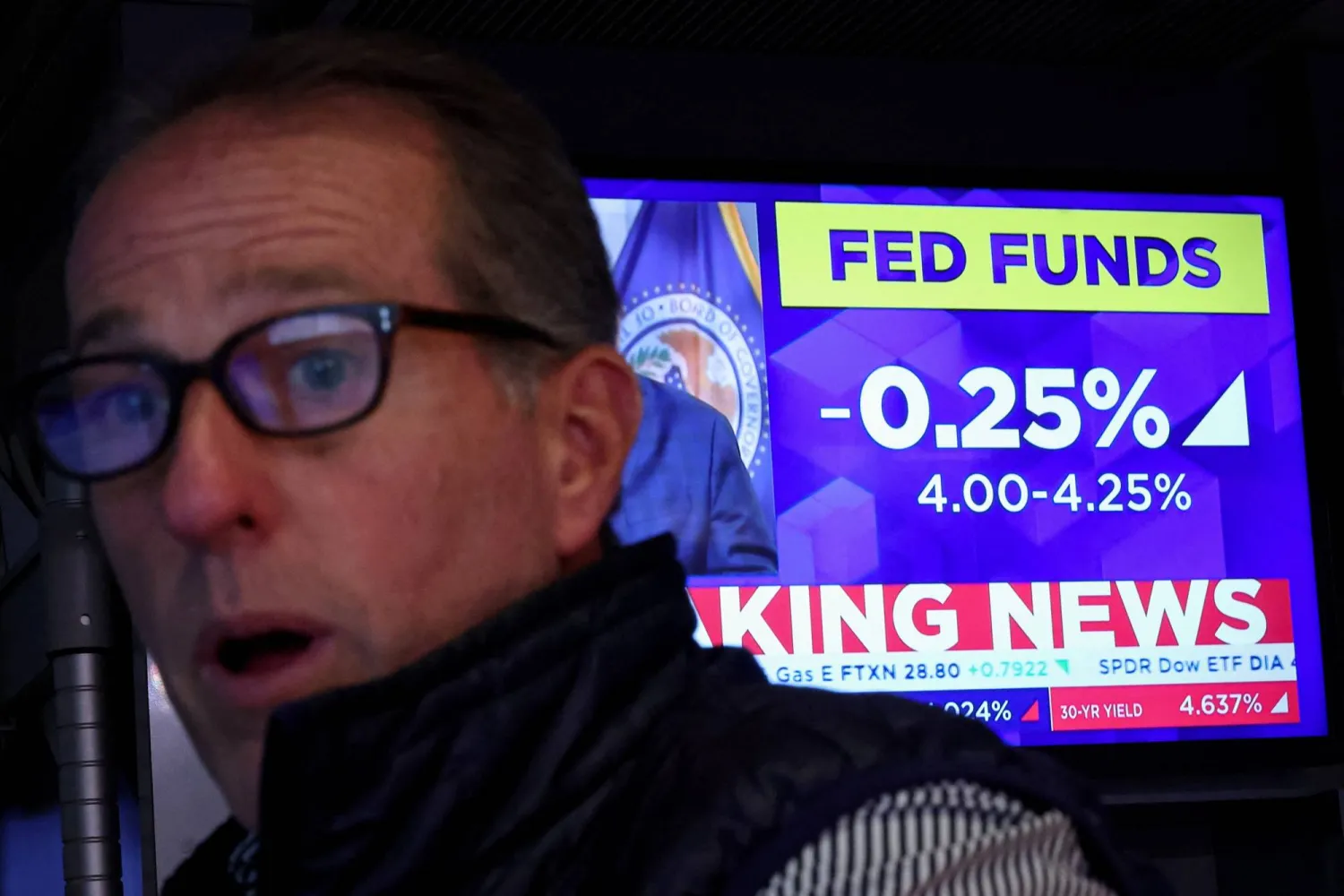 متداول في بورصة نيويورك يتفاعل بينما تعرض الشاشة إعلان خفض الفائدة بمقدار 25 نقطة أساس (رويترز)