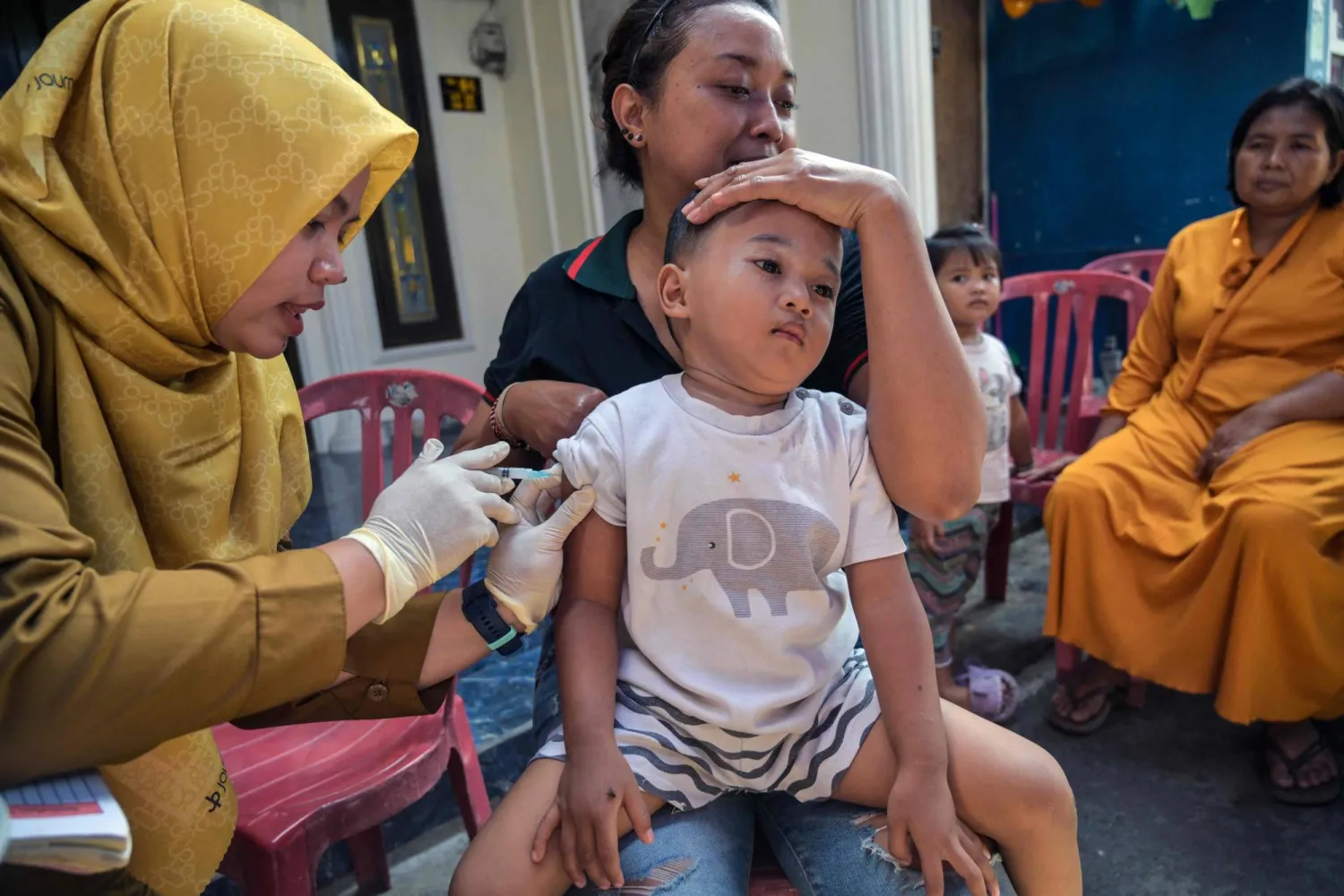 عاملة صحية تعطي لقاحاً ضد الحصبة لطفل في سورابايا بإندونيسيا (أ.ف.ب)