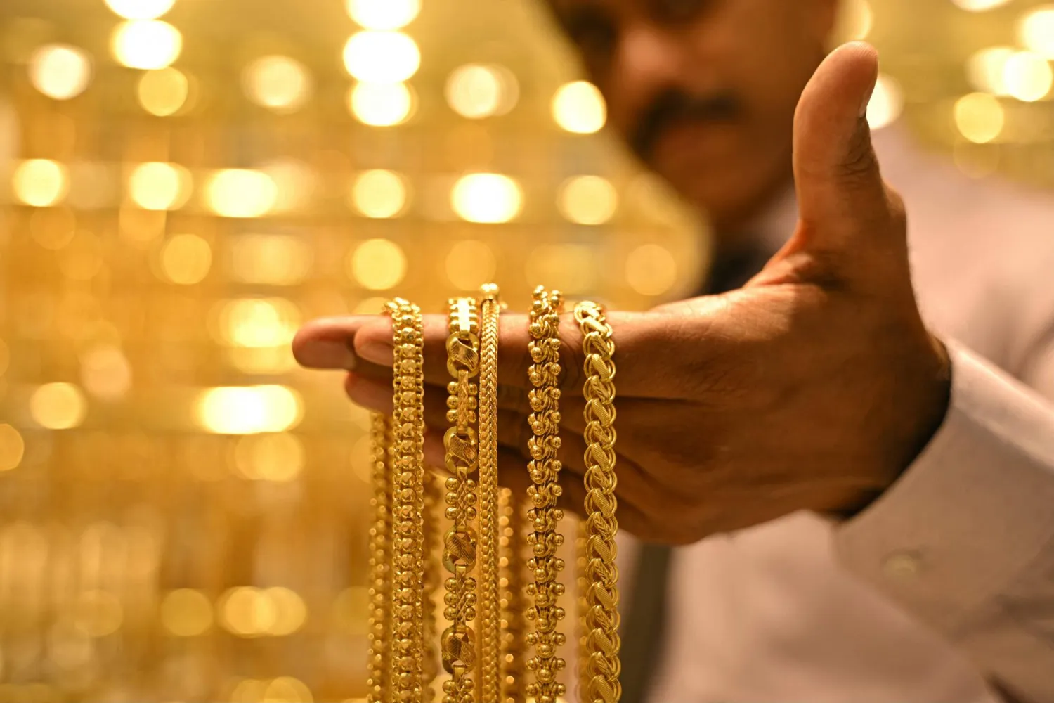 A salesman displays gold chains, at Jos Alukkas jewelry store in Bengaluru on September 17, 2025. I(Photo by Idrees MOHAMMED / AFP)