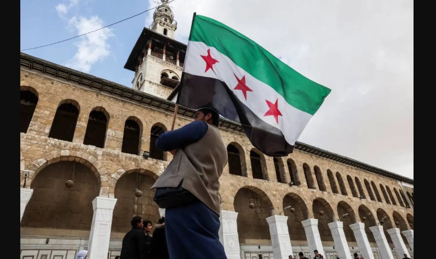 رجل يحمل العلم السوري في الجامع الأموي بدمشق (رويترز)