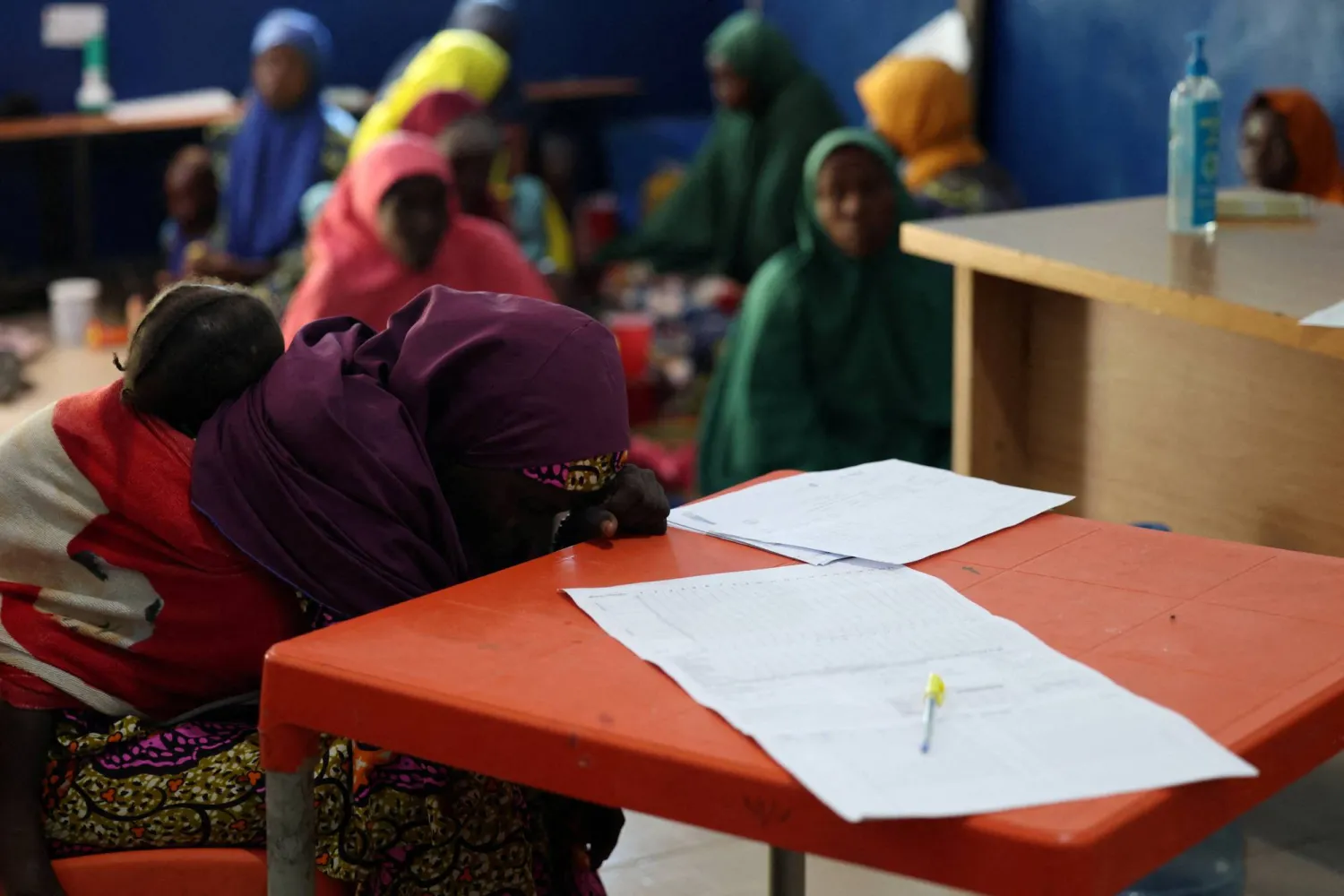 A woman sits with her malnourished child as they wait for treatment at the emergency ward of Dikwa Primary Health Center, where children are stabilized for severe malnutrition, in Dikwa, Borno State, Nigeria, August 27, 2025. REUTERS/Sodiq Adelakun