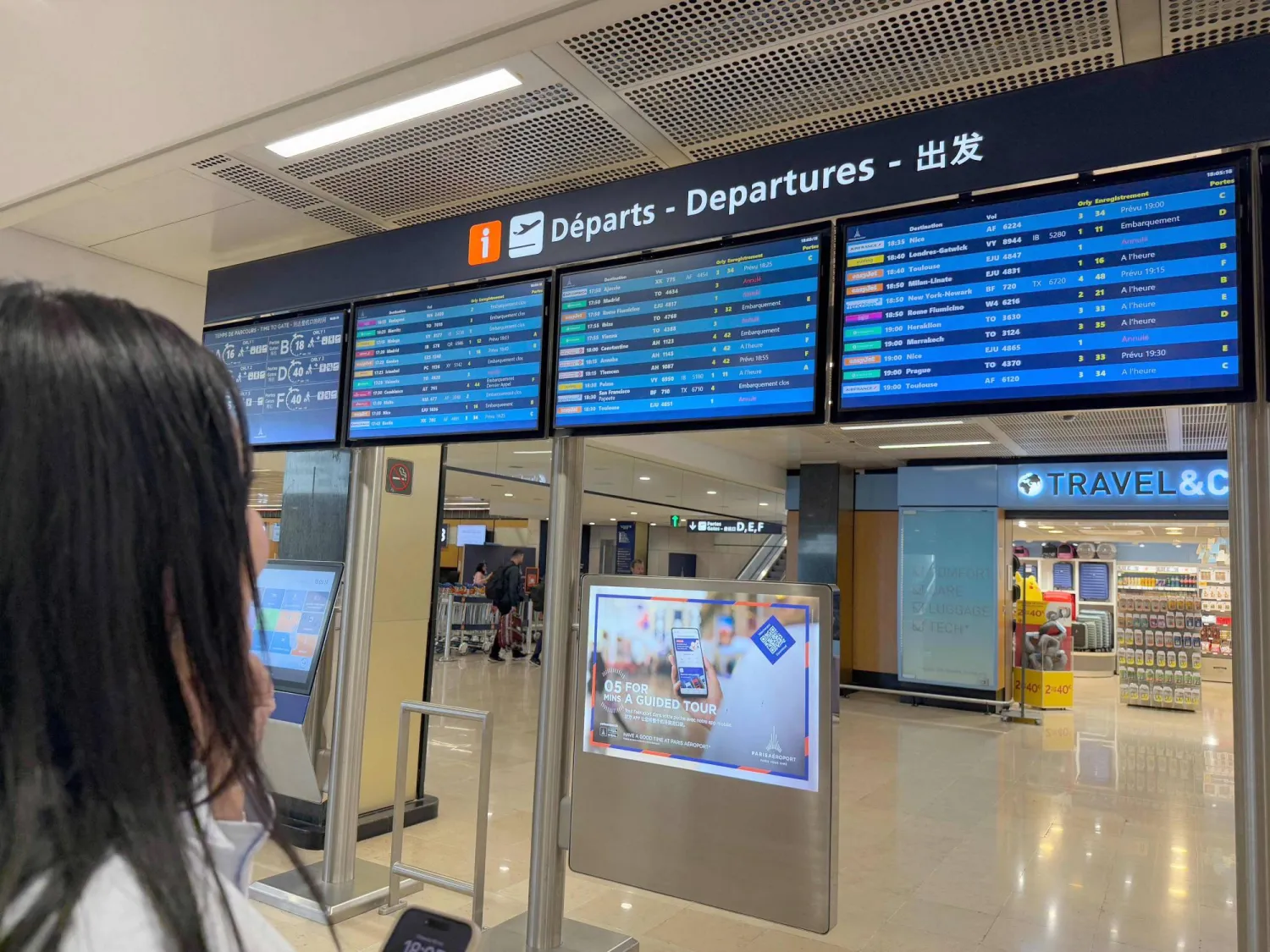 سيدة تقف أمام جدول وصول الرحلات الجوي في مطار باريس - أورلي جنوب فرنسا (أ.ف.ب)