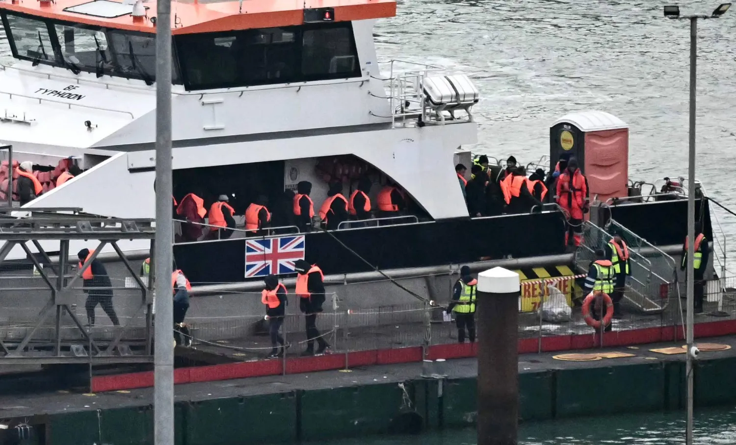 مهاجرون تم إنقاذهم في البحر أثناء محاولتهم عبور القنال الإنجليزية من فرنسا ينزلون من سفينة «تايفون» التابعة لقوة الحدود بعد وصولها إلى مارينا دوفر بجنوب شرقي إنجلترا يوم 13 يناير 2025 (أ.ف.ب)