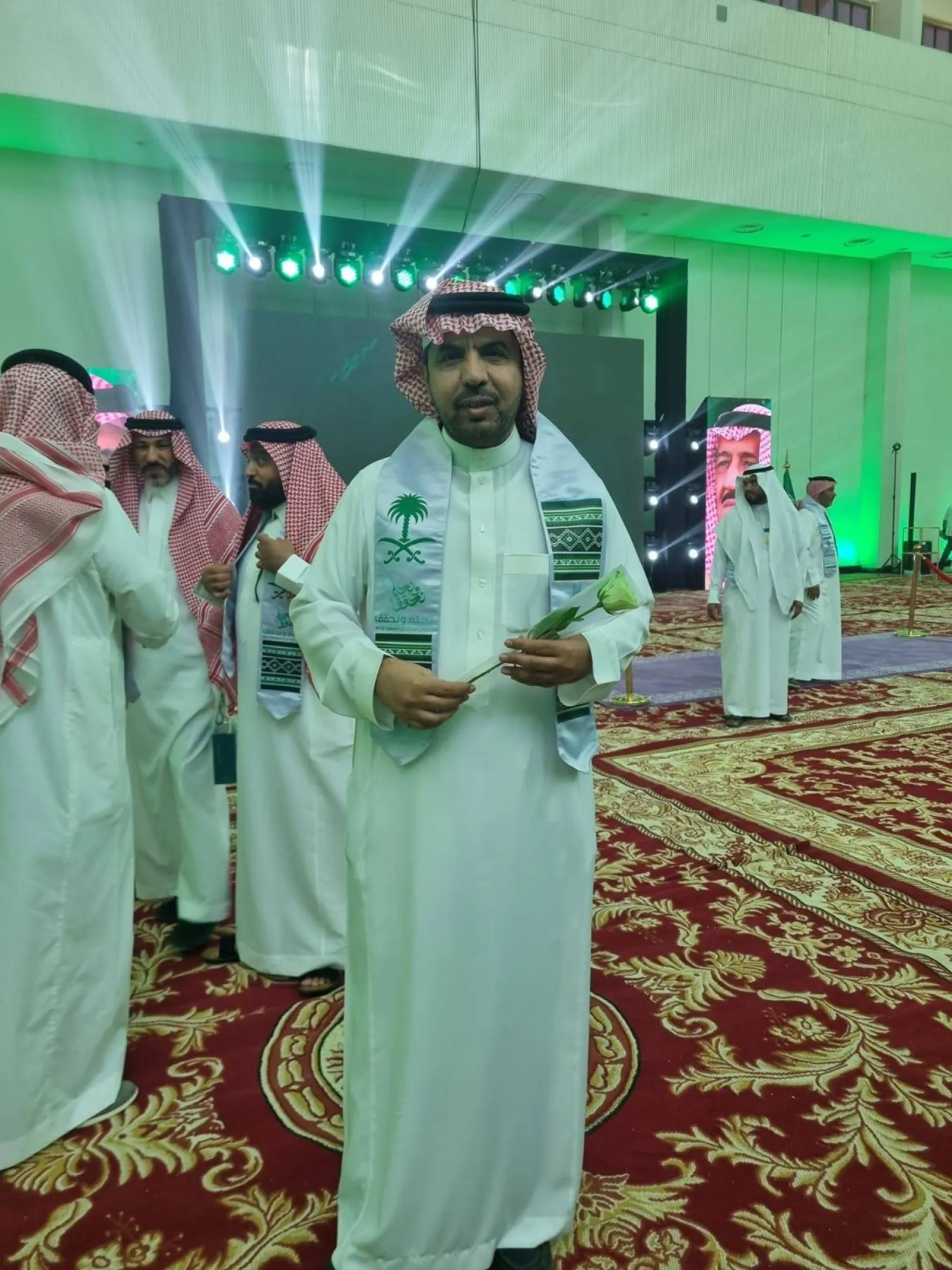 الدكتور عبد الرحمن الشقير متوشحاً شعار اليوم الوطني وحاملاً علم بلاده (الشرق الأوسط)