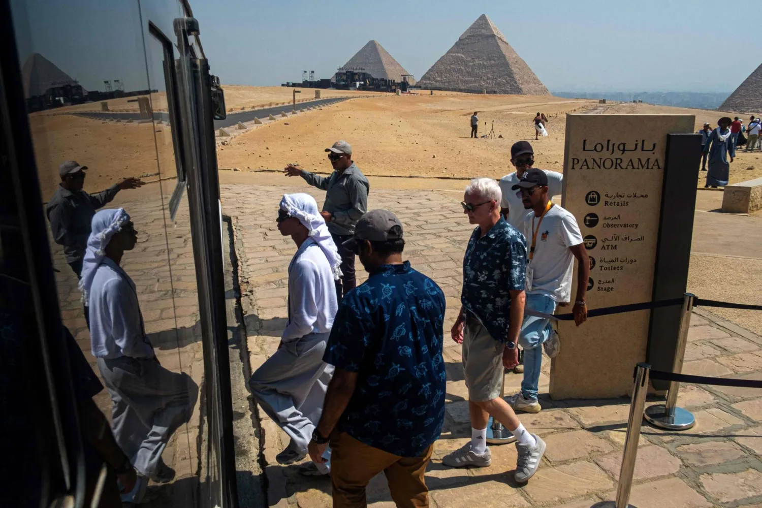 Tourists board an environmentally friendly electric bus, during their visit to the Giza Pyramids necropolis, on the southwestern outskirts of the Egyptian capital Cairo on September 18, 2025. (Photo by Khaled DESOUKI / AFP)
