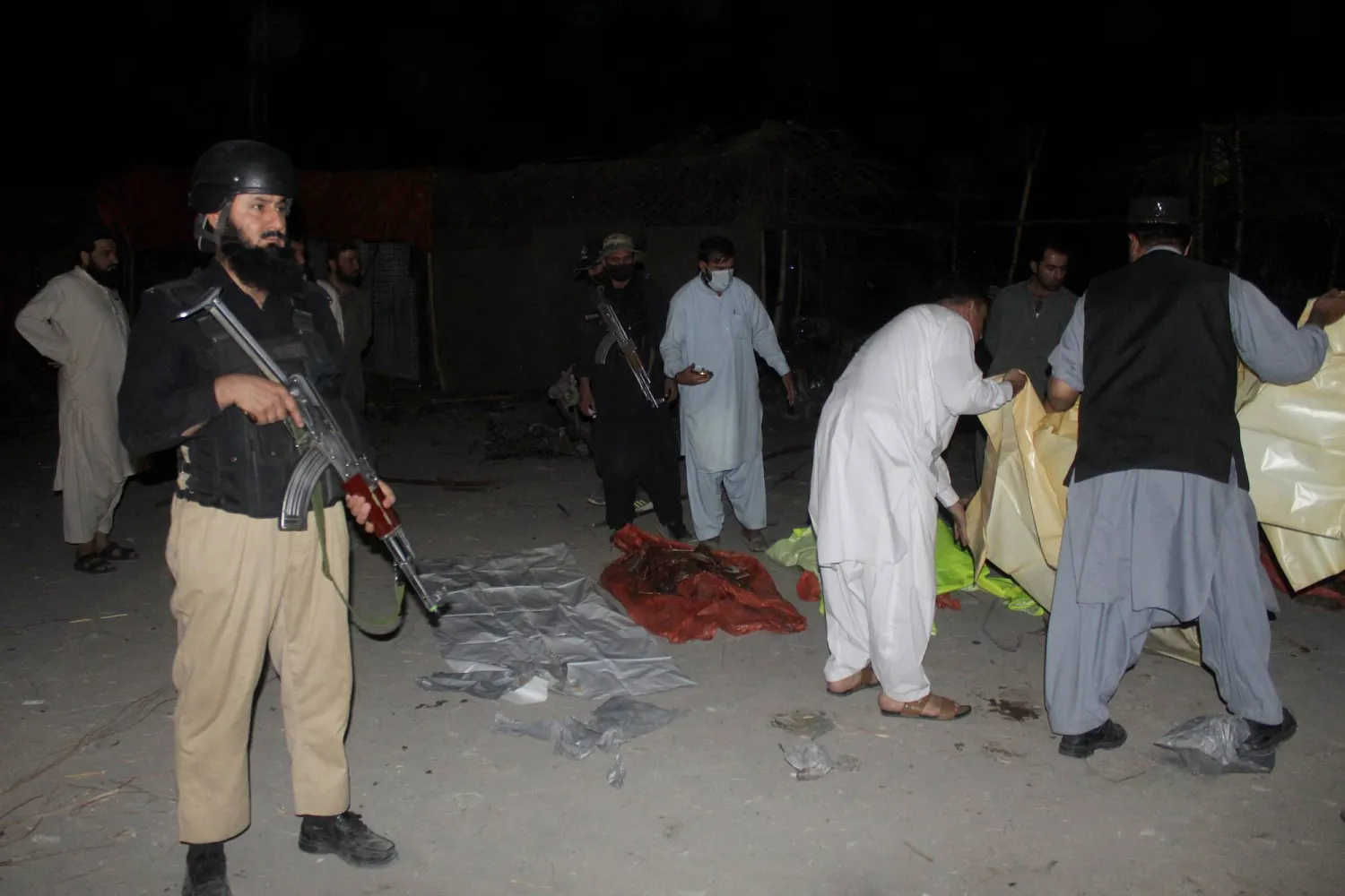 In this picture taken on September 18, 2025, security personnel stand beside the bodies of victims who died in a blast near the Pakistan-Afghanistan border in Chaman. (Photo by Abdul BASIT / AFP)