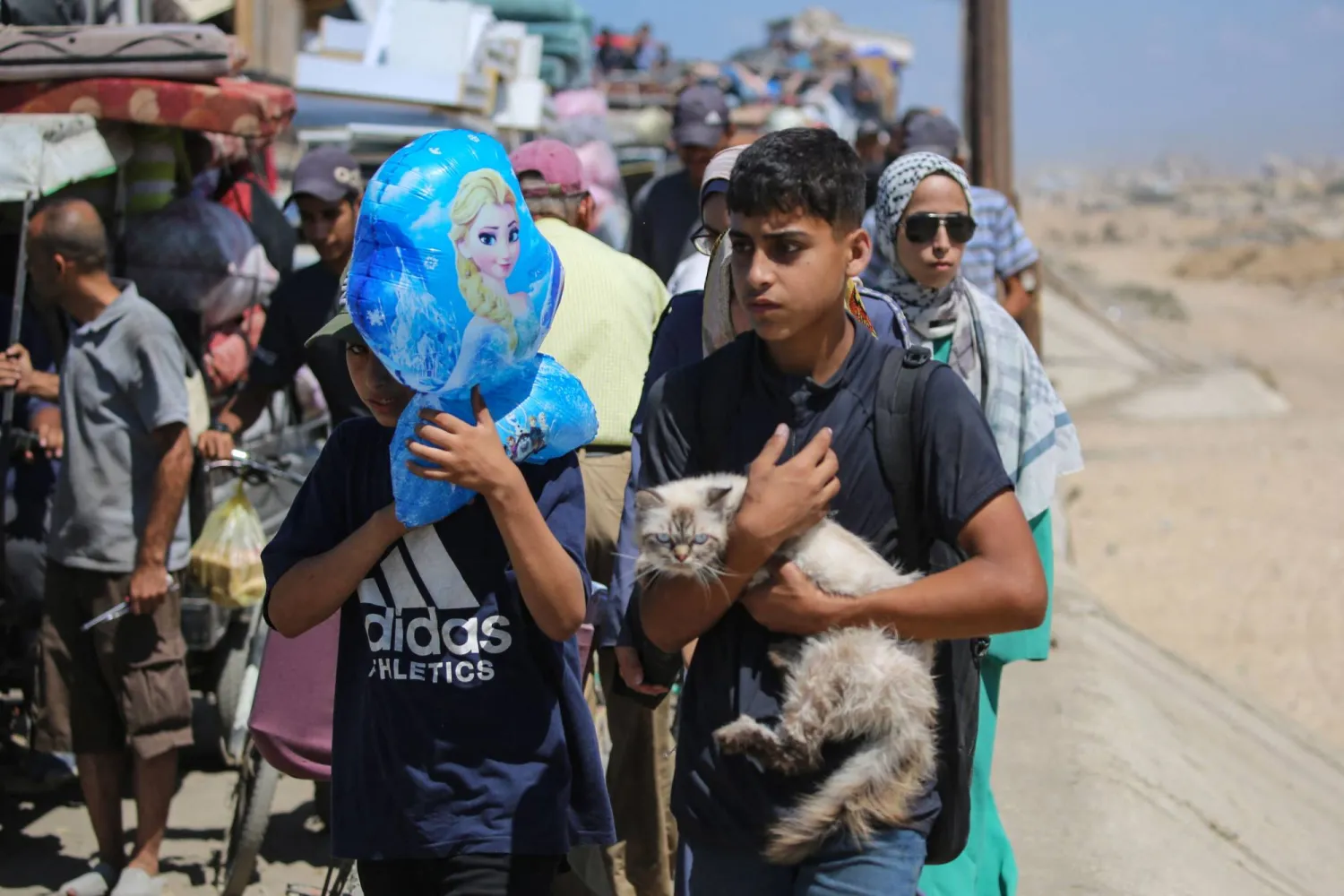 صبي يحمل قطة في حين ينزح مع كثيرين باتجاه جنوب قطاع غزة عبر الطريق الساحلي قرب مخيم النصيرات الجمعة (أ.ف.ب)